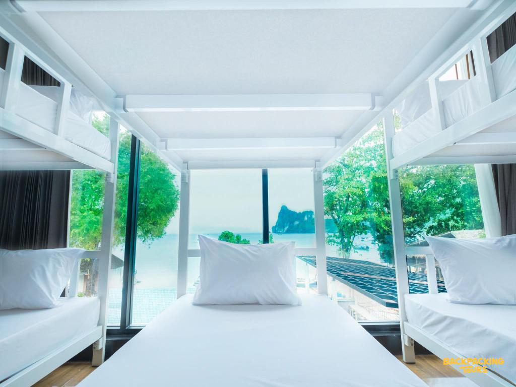 A clean, modern hostel dorm room with white bunk beds overlooking the beautiful Koh Phi Phi ocean.