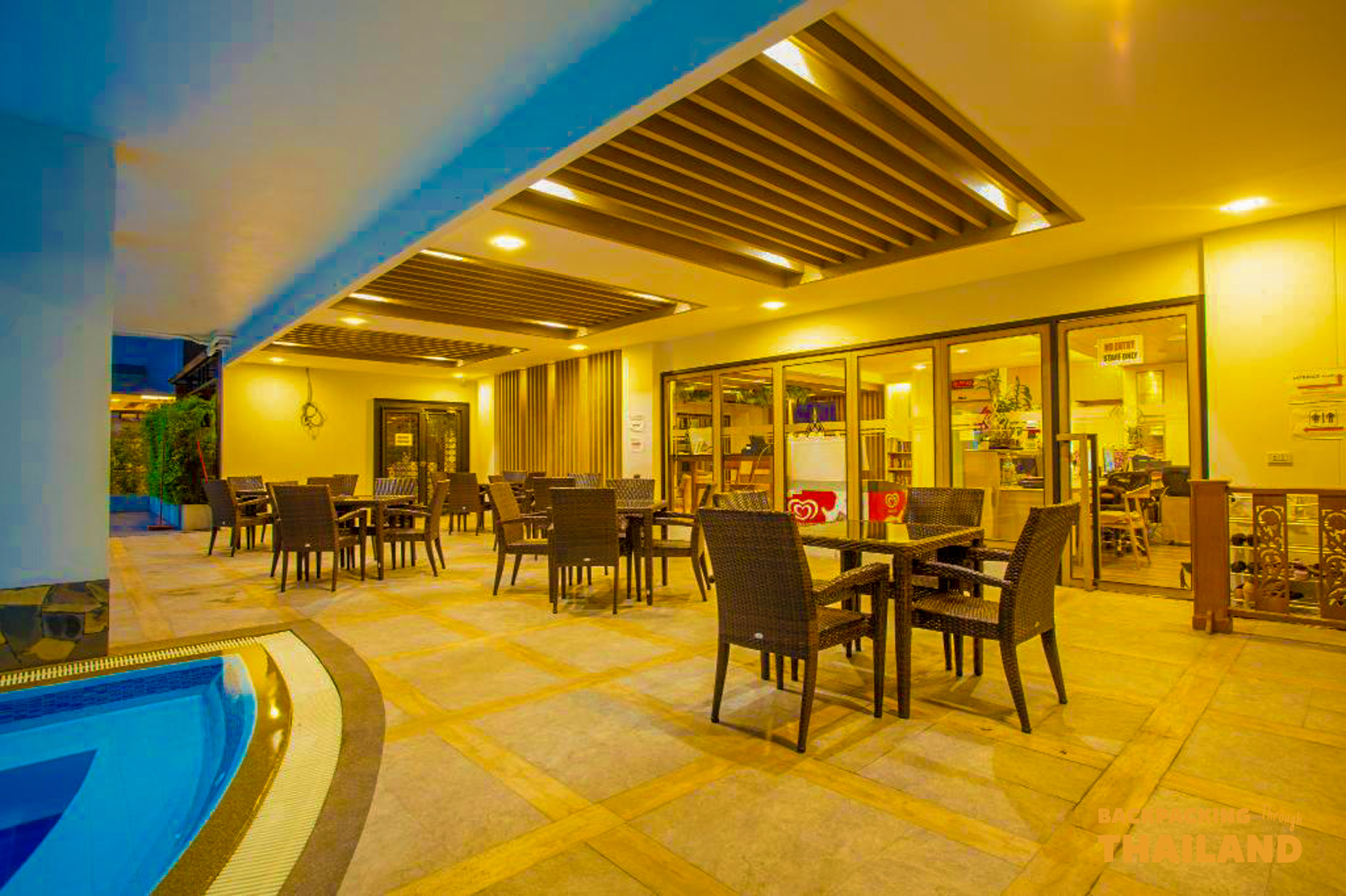 An inviting outdoor dining area with comfortable seating and a small swimming pool at your Bangkok hotel.