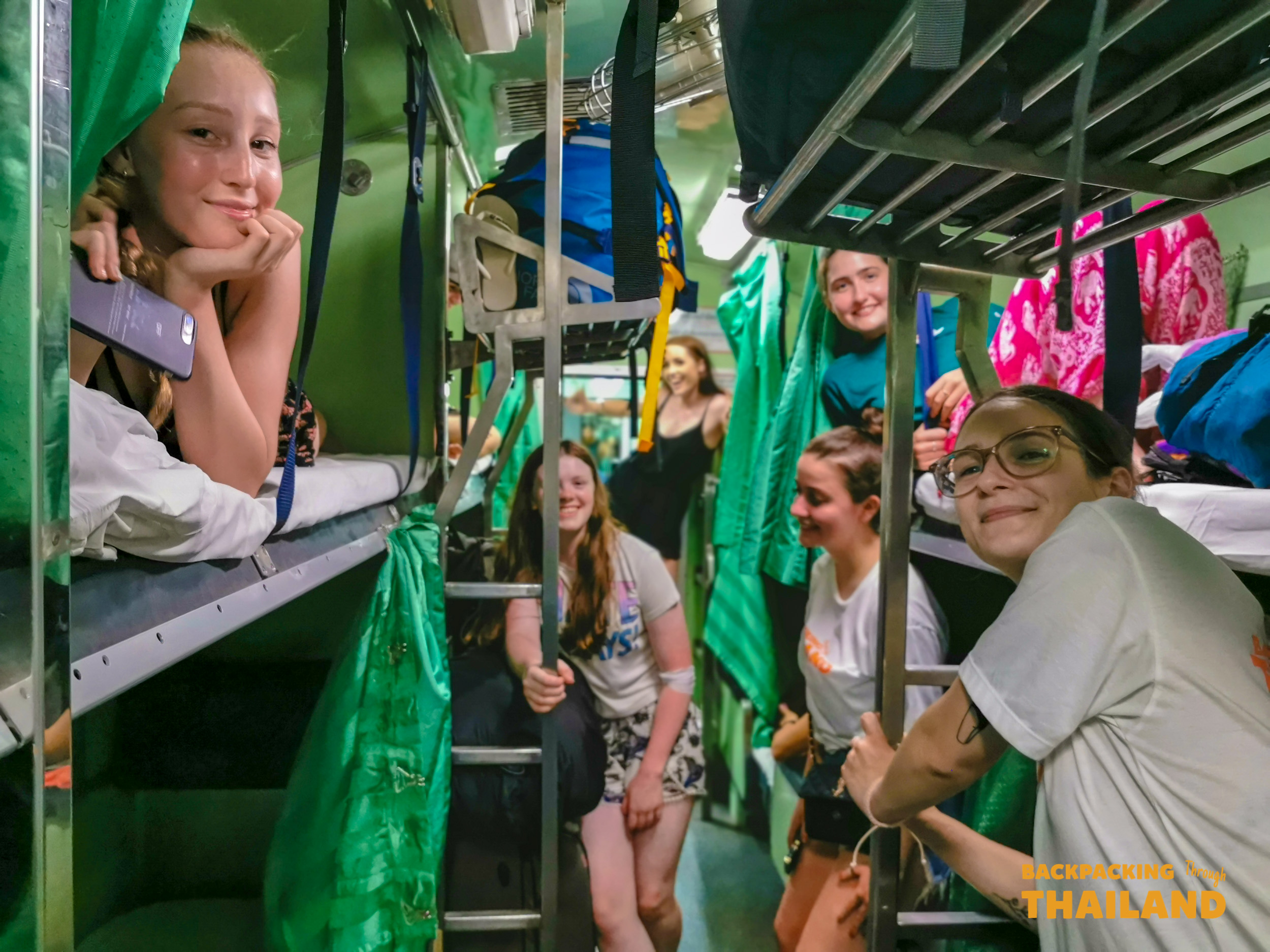 Backpacking group on green-curtain sleeper train in Thailand.