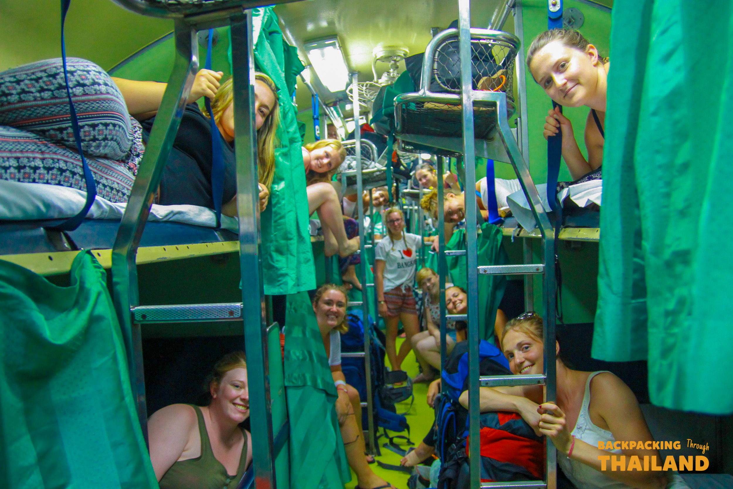 Smiling backpacker girl sitting on bunk bed in Thai night train.