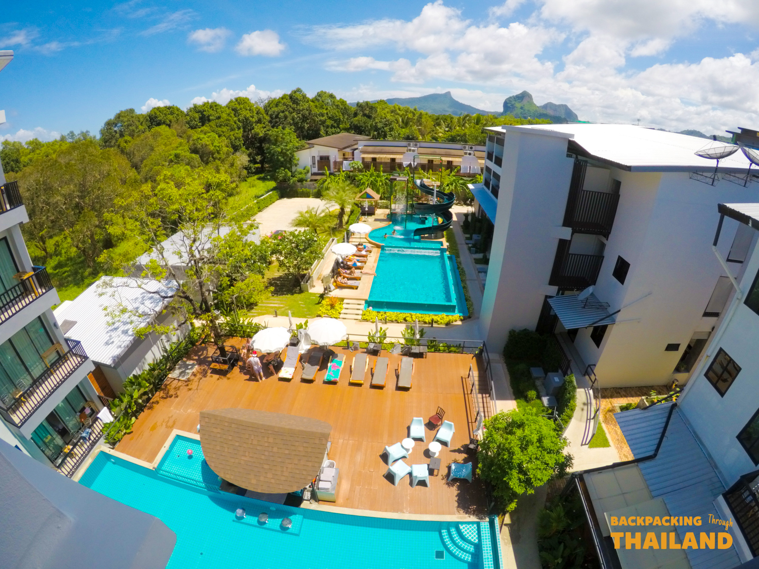 Relaxing resort pools and modern buildings surrounded by tropical greenery under a sunny Krabi sky.