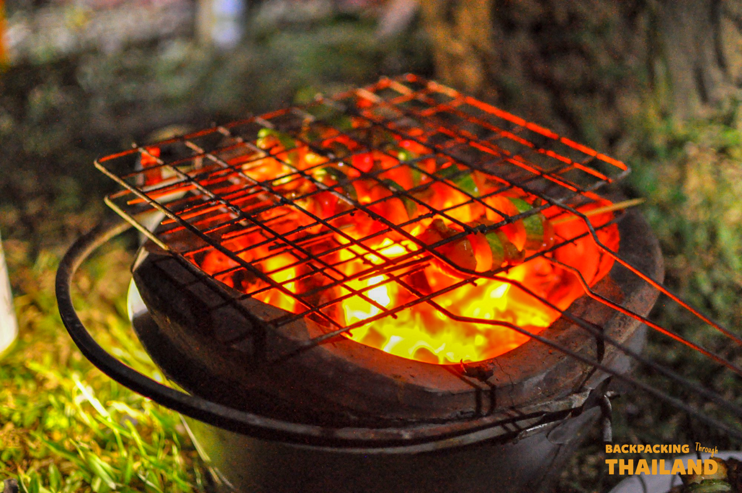 Close-up of a charcoal grill with glowing coals at the campsite