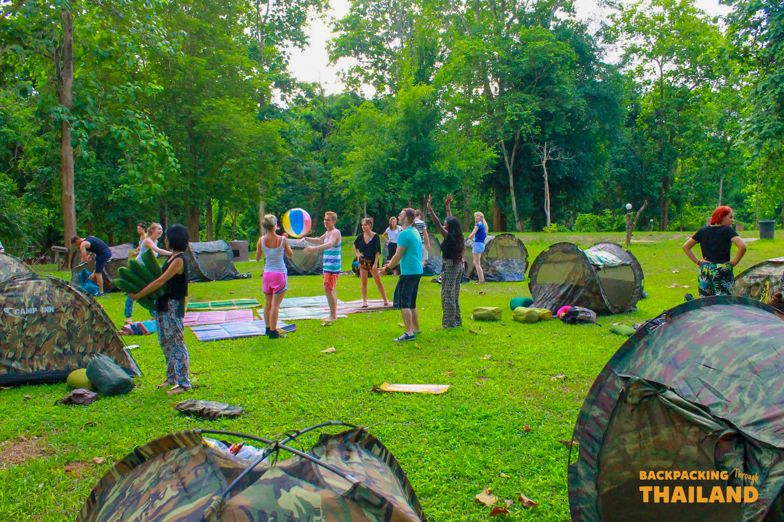Backpacking group playing football on a grassy field at the campsite