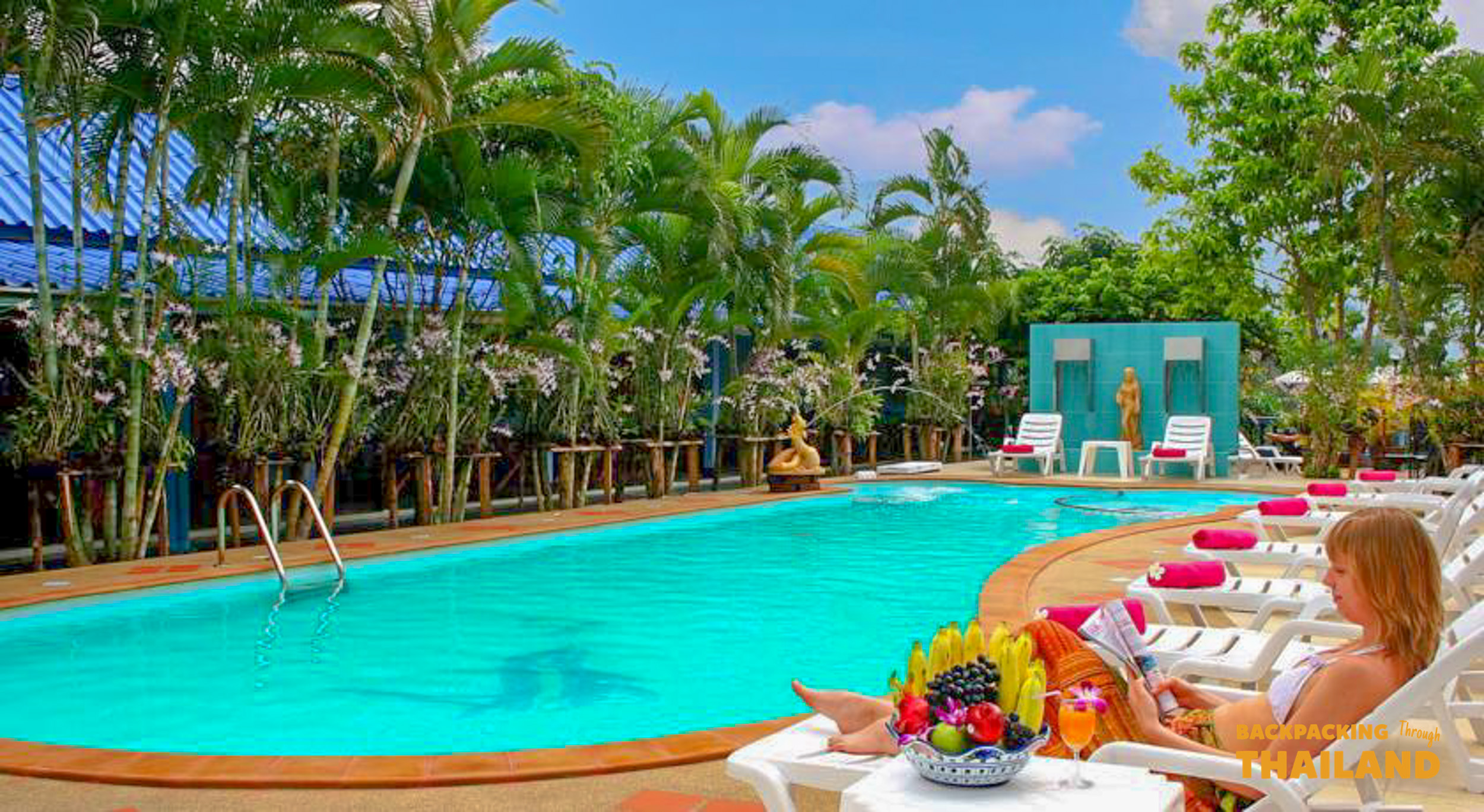 Outdoor swimming pool with lounge chairs and palm trees at the resort