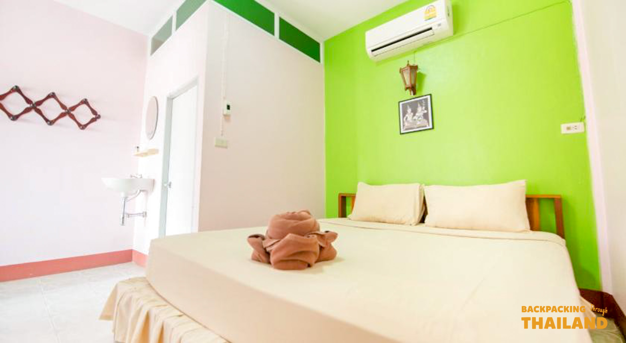 A simple and colorful guesthouse room in Kanchanaburi, Thailand, with a comfortable bed.