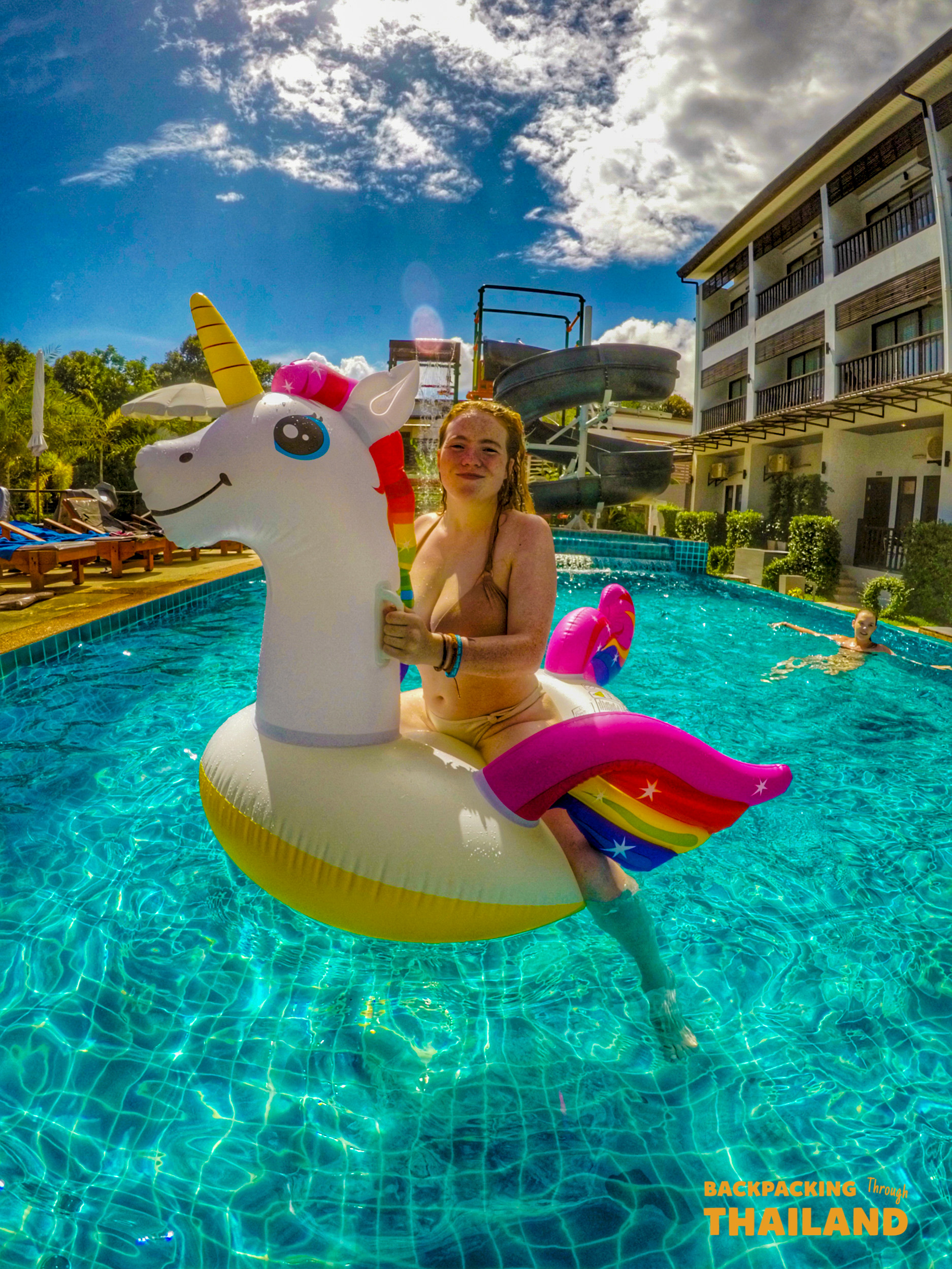 A young woman enjoys free time floating on a unicorn in a resort pool in Krabi.