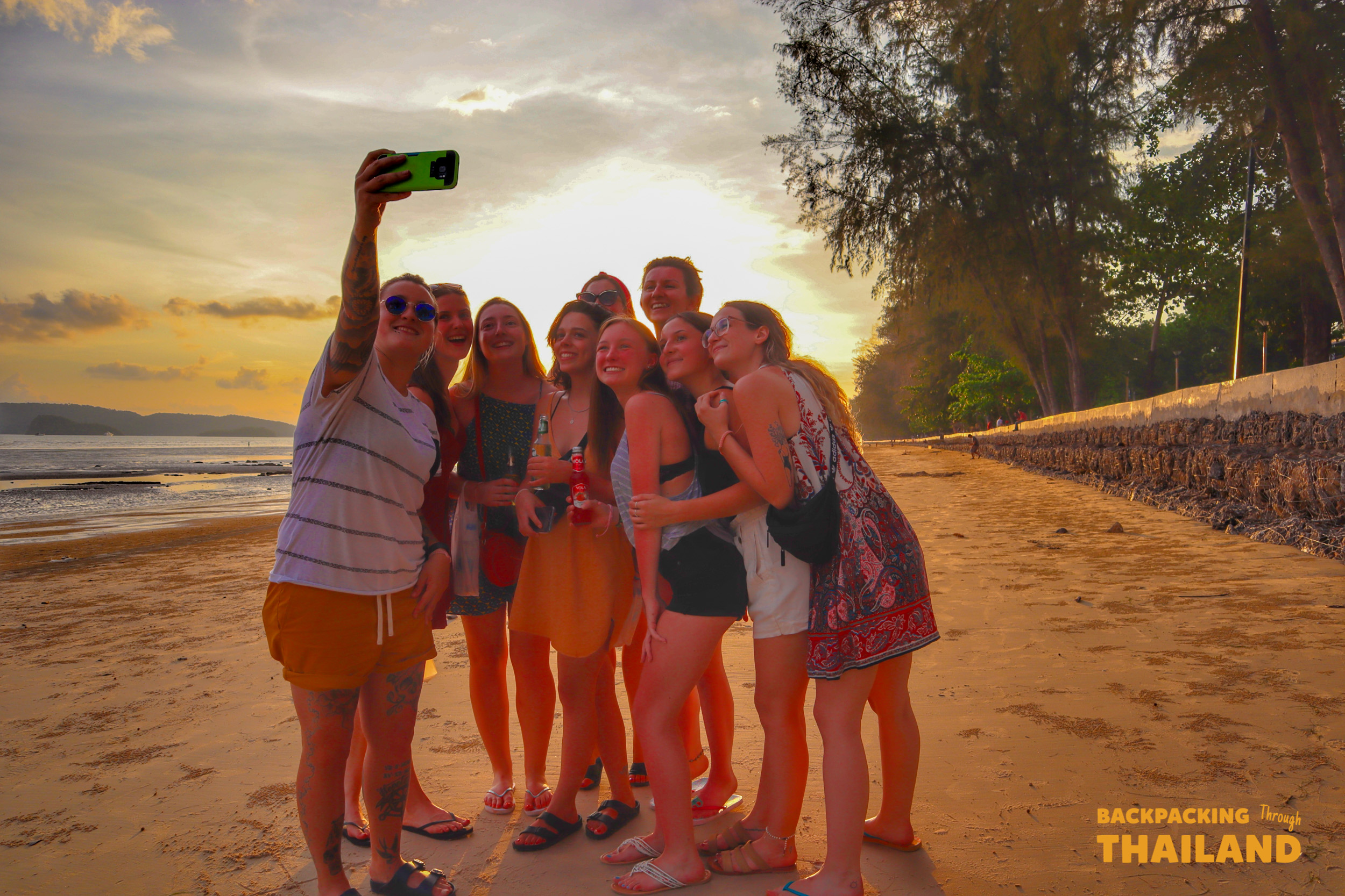 Happy backpackers capture a sunset selfie on a beautiful beach in Krabi, Thailand.