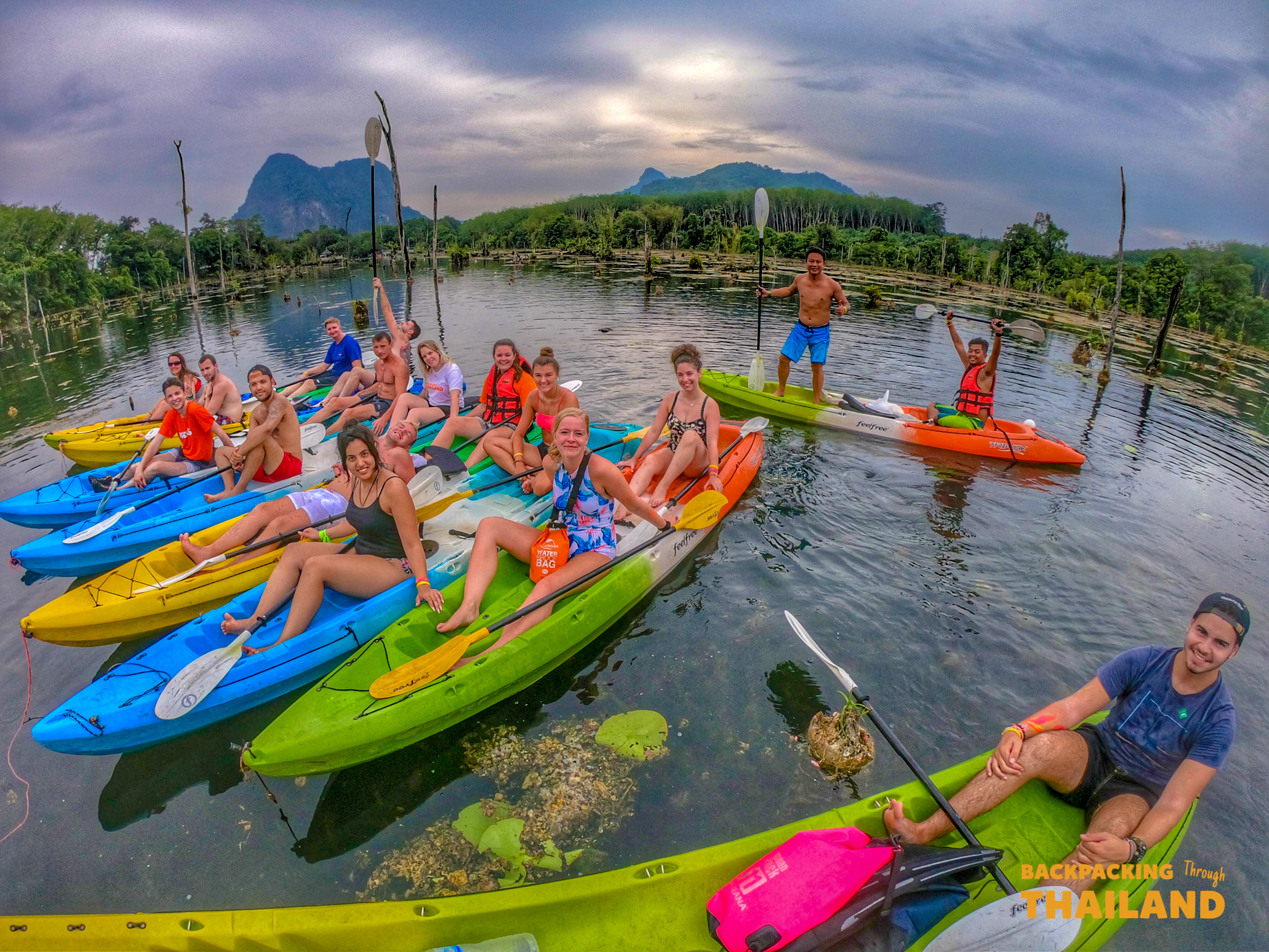 Happy backpackers enjoy a mangrove kayak adventure in the clear waters of Krabi, Thailand.