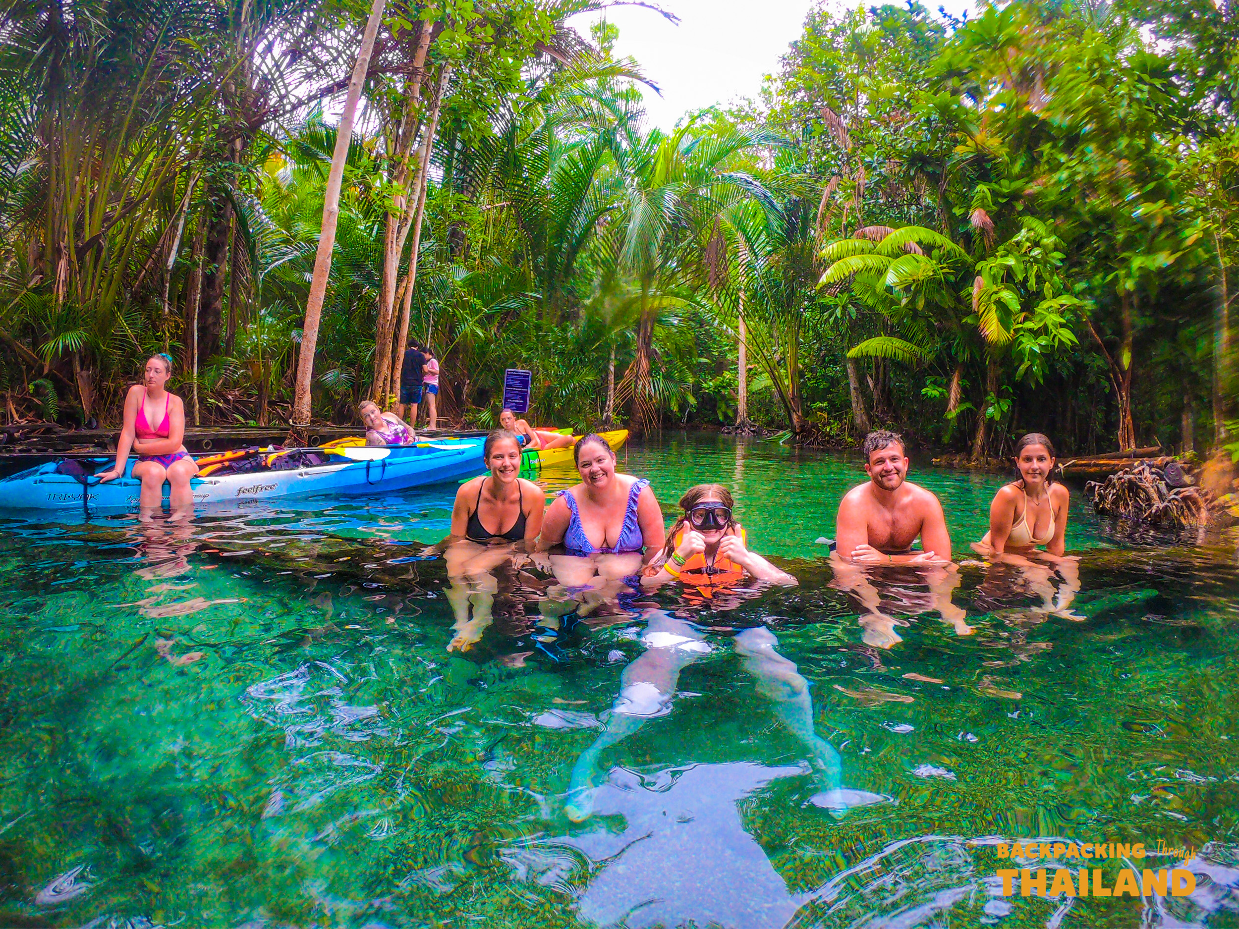 Friends cooling off in the crystal-clear emerald river during a kayak adventure in Krabi.