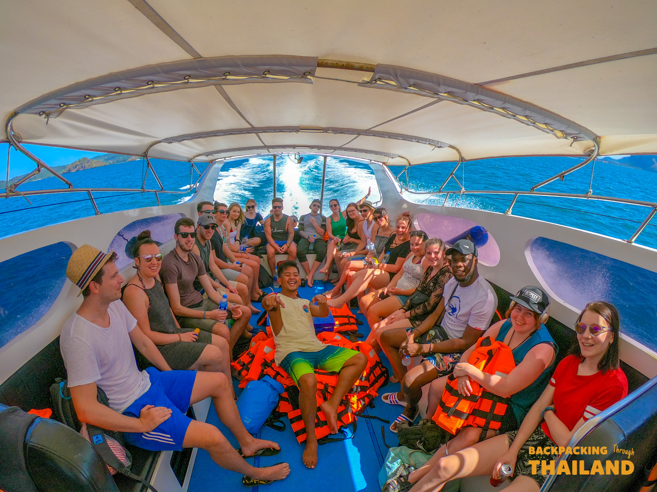Smiling backpackers enjoy a speed boat ride on the clear blue waters around Koh Phi Phi.