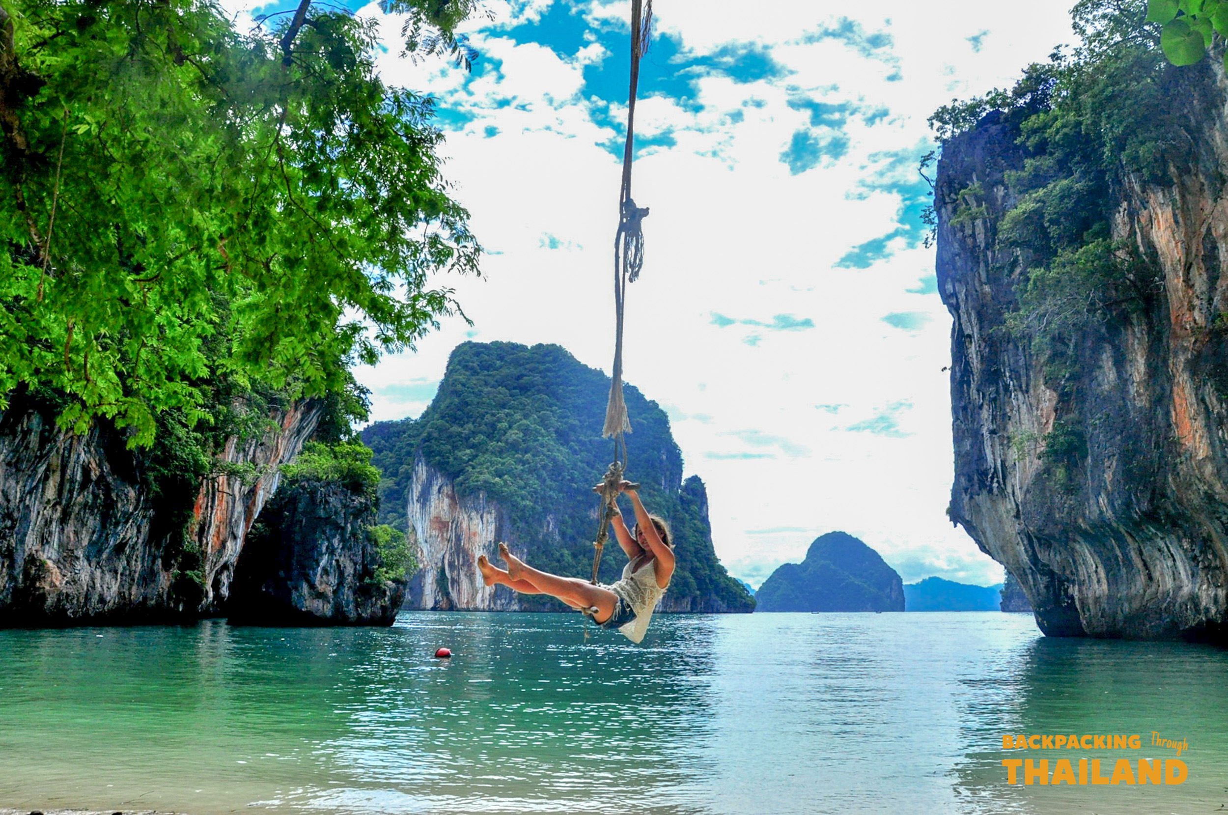 A backpacker joyfully swings on a rope over the stunning turquoise waters of Koh Phi Phi, Thailand.