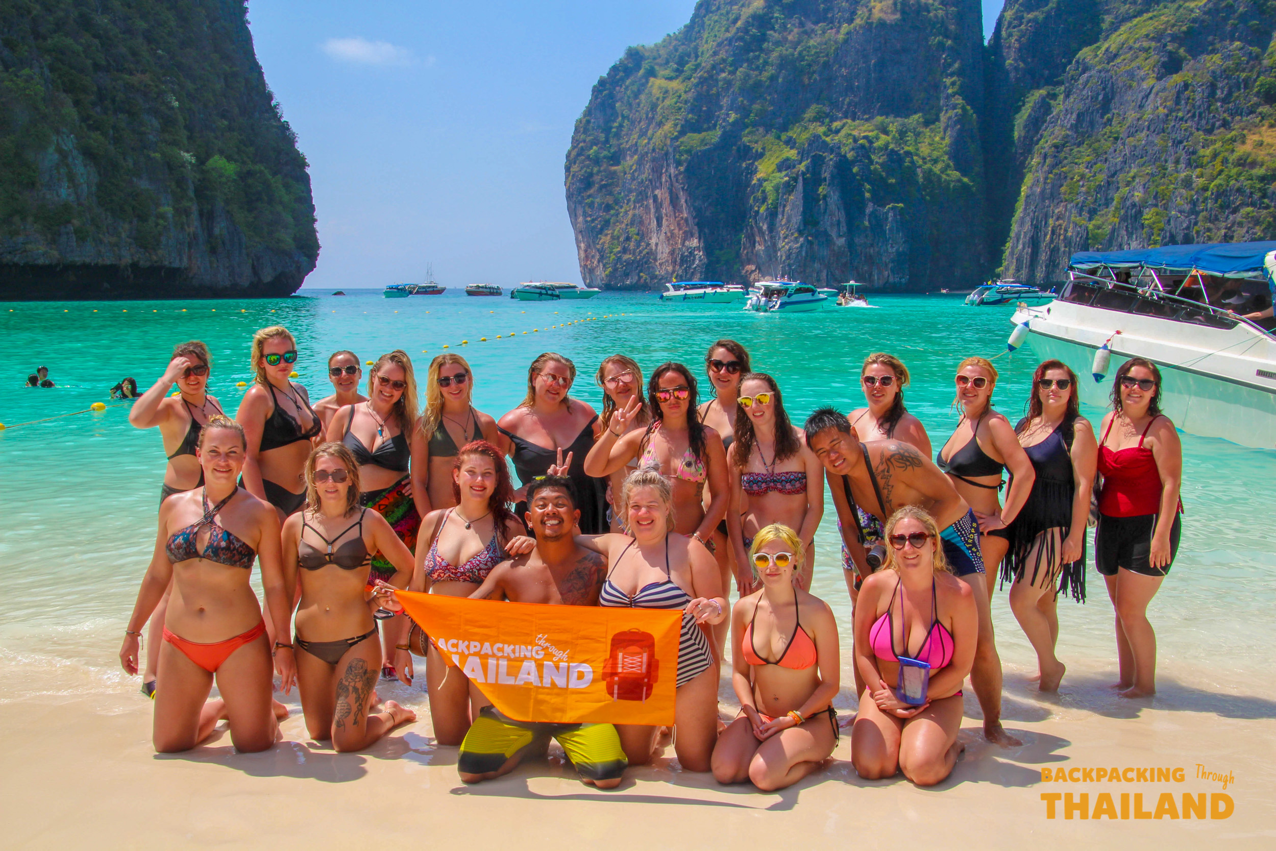 Happy backpackers pose on the beautiful white sand beach of Koh Phi Phi, Thailand.