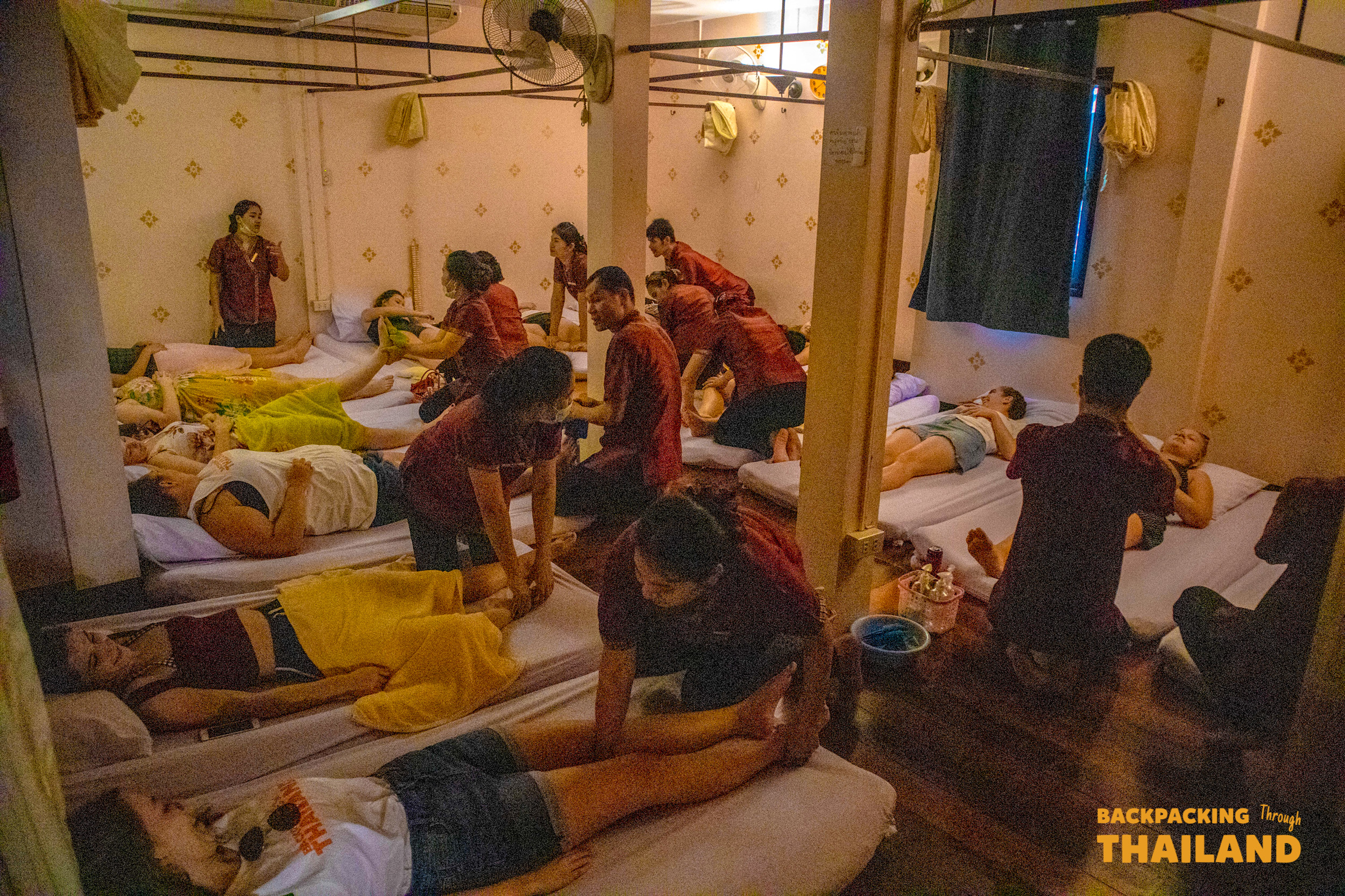 Tourists enjoy a relaxing traditional Thai massage in a bustling parlor in Bangkok.