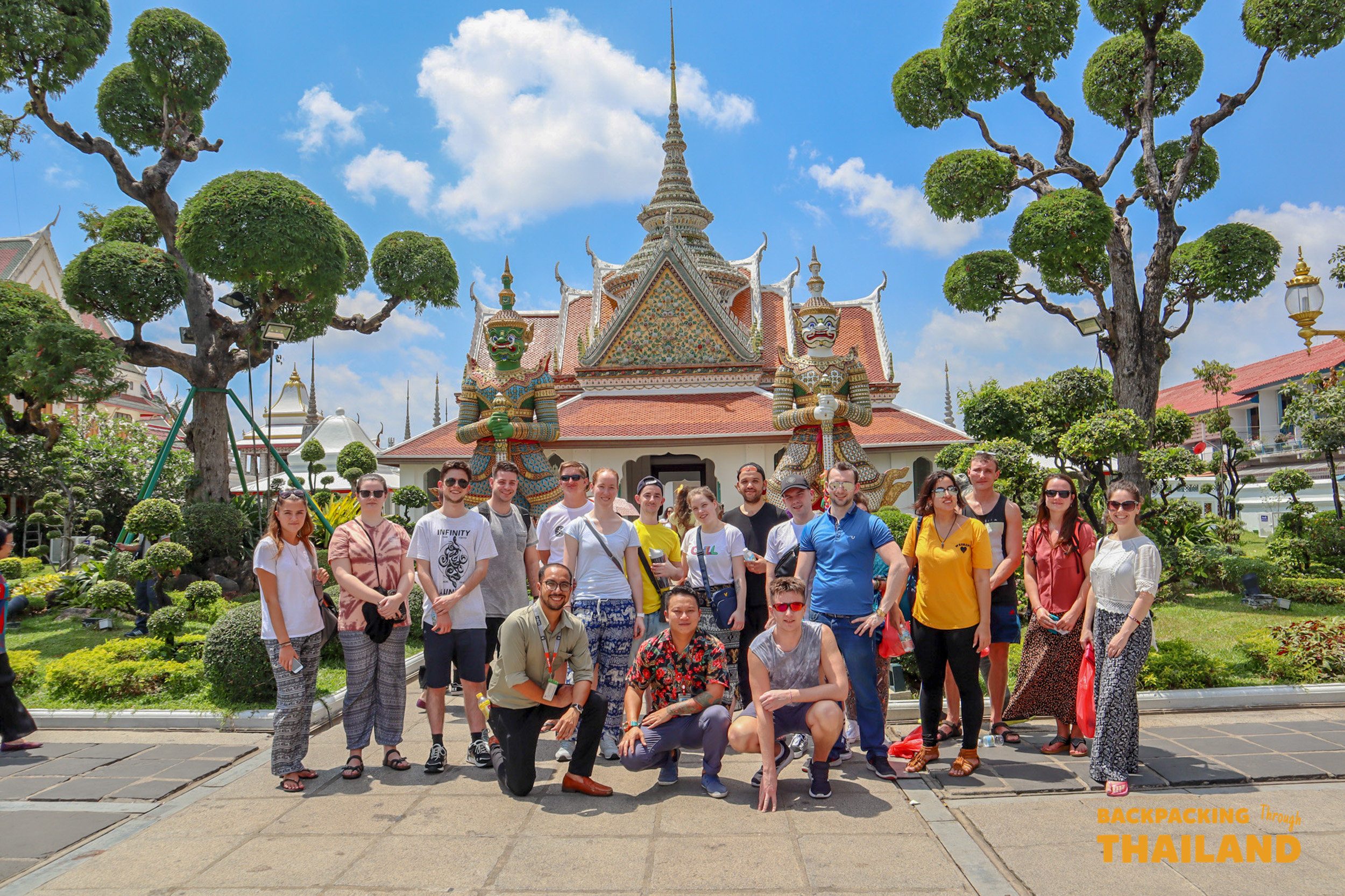 Happy backpackers pose for a group photo at the beautiful Wat Arun temple in Bangkok.