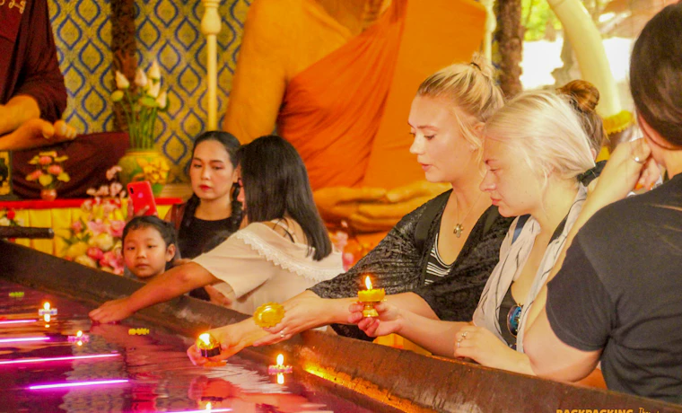 Travelers respectfully float candles in a purple pool inside a temple in Ayutthaya, Thailand.