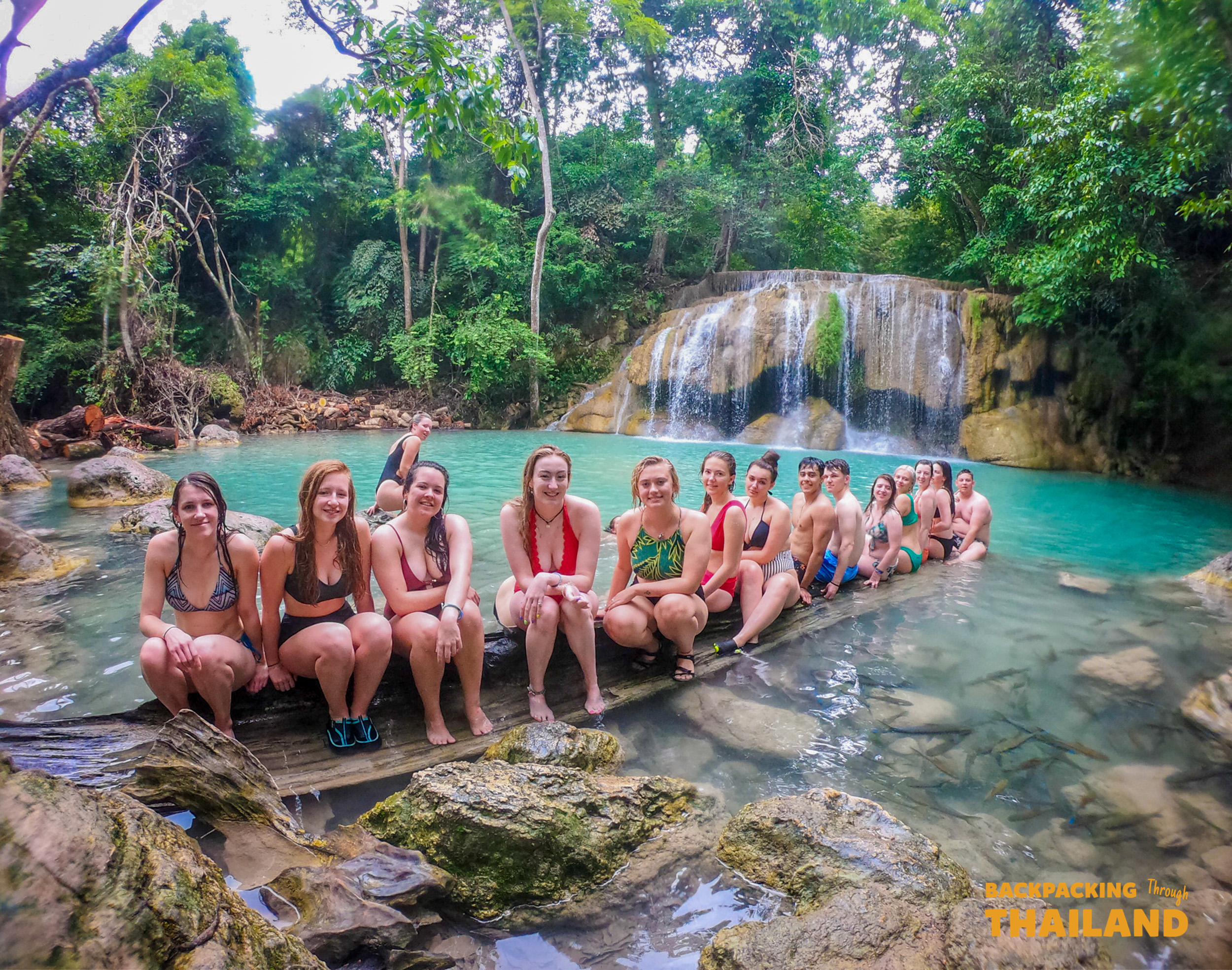 Happy travelers enjoying the refreshing emerald pools and waterfalls in Thailand's Erawan National Park.