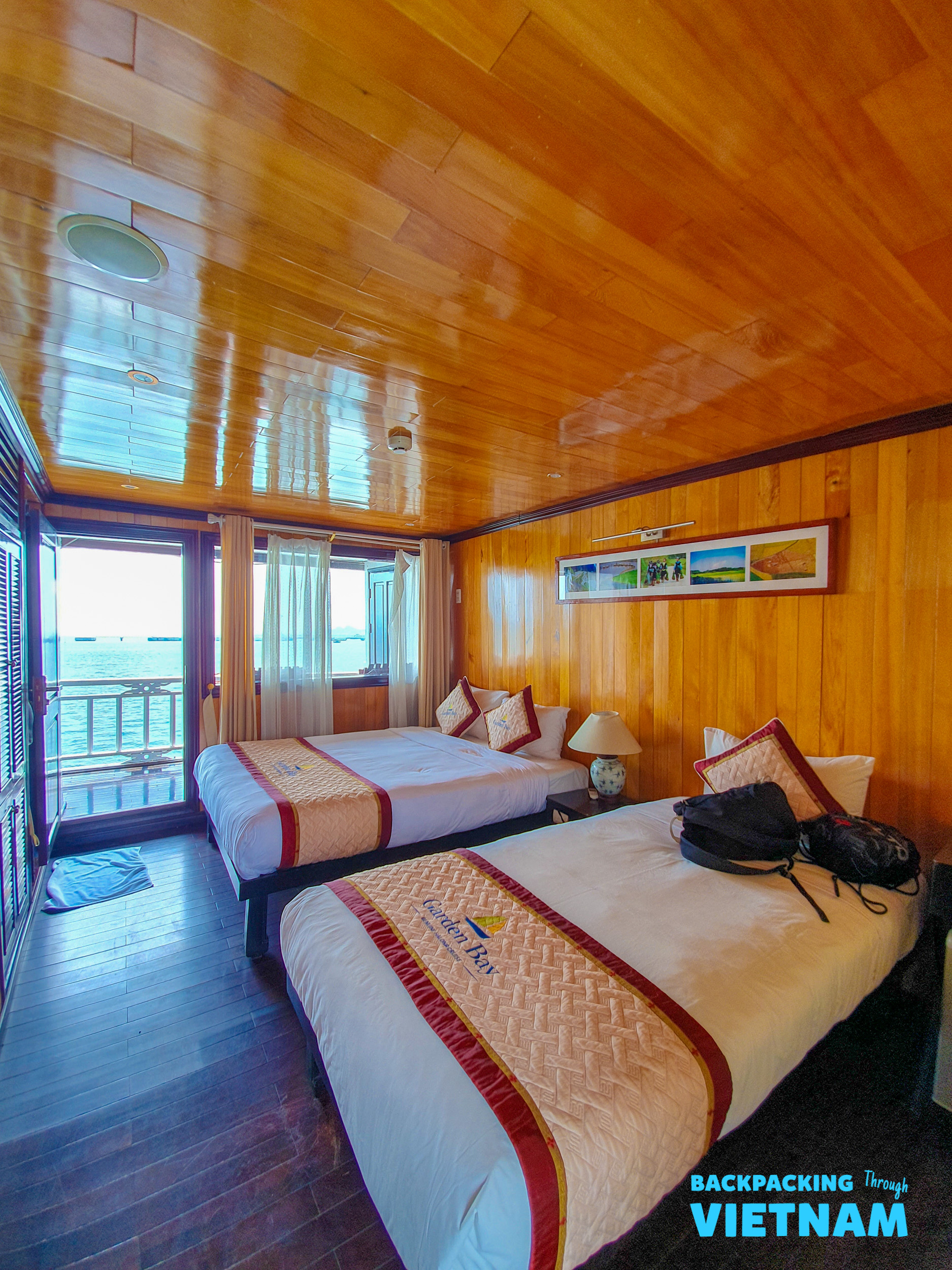 Cozy wooden cabin with two comfortable beds and a sea view on a Halong Bay sleeper boat.