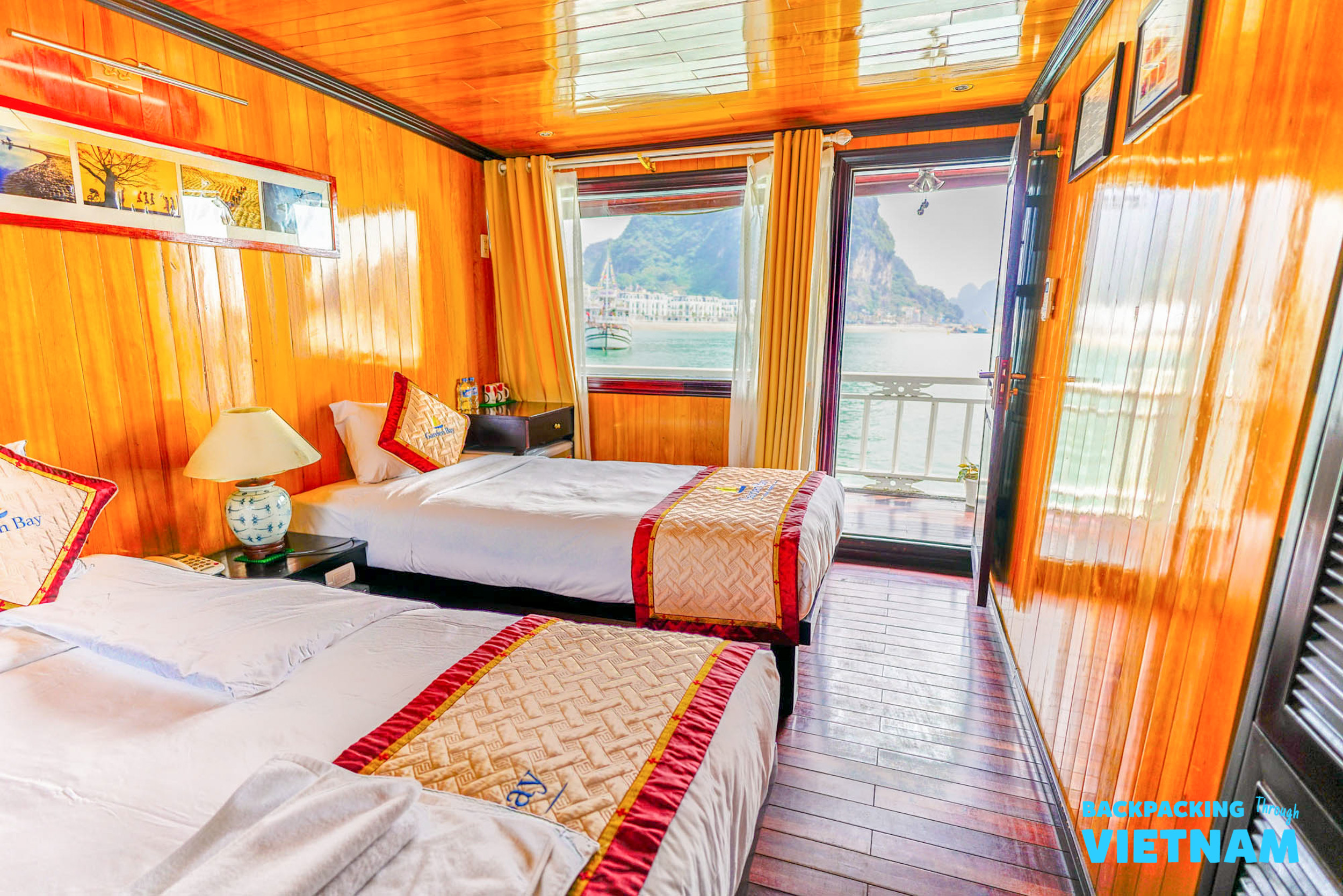 Comfortable twin beds in a boat cabin with a balcony overlooking the beautiful Halong Bay.