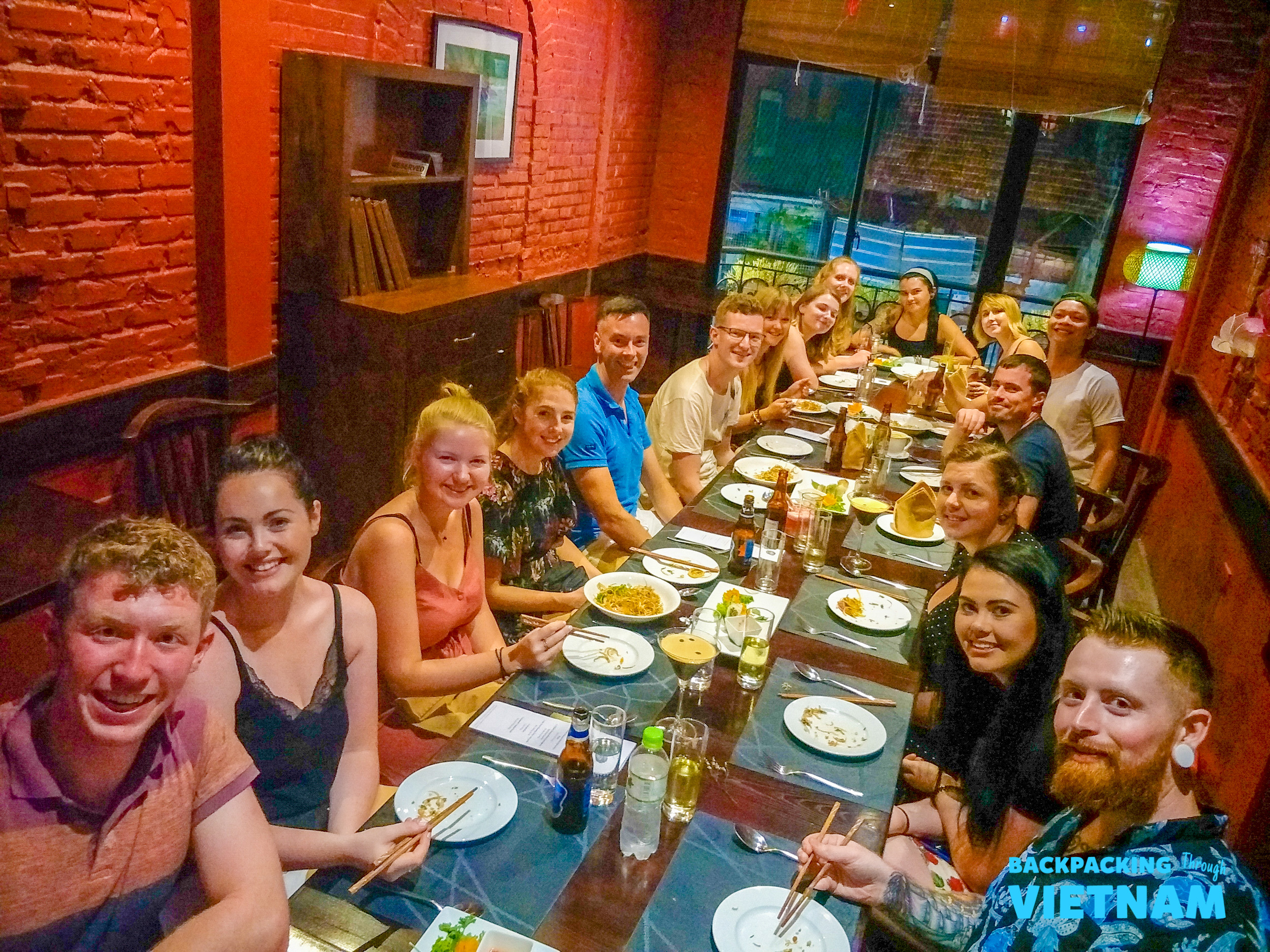 A group of happy young travelers enjoying a delicious welcoming dinner together in Hanoi, Vietnam.
