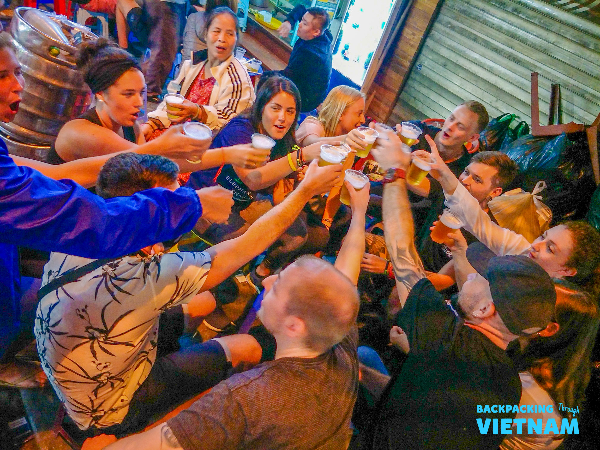 A group of happy backpackers cheers with beers during a lively night out in Hanoi.