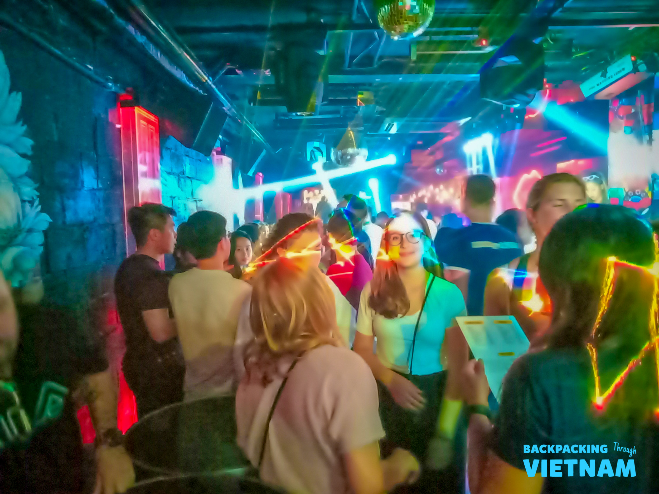 Young backpackers enjoy a lively night out dancing and socializing in a vibrant club in Hanoi.