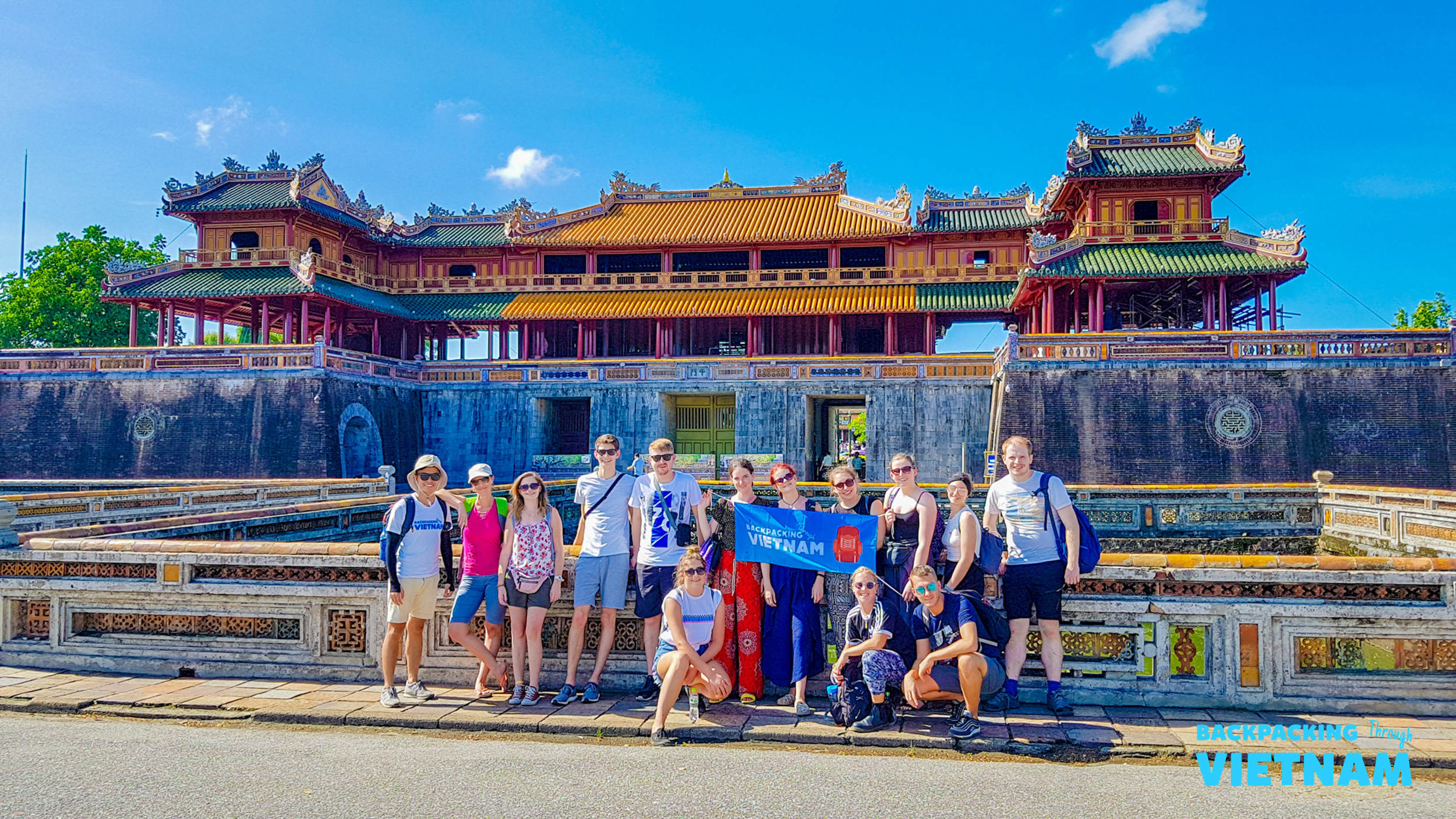 Our group of backpackers smiles in front of the majestic Imperial City in Hue, Vietnam.