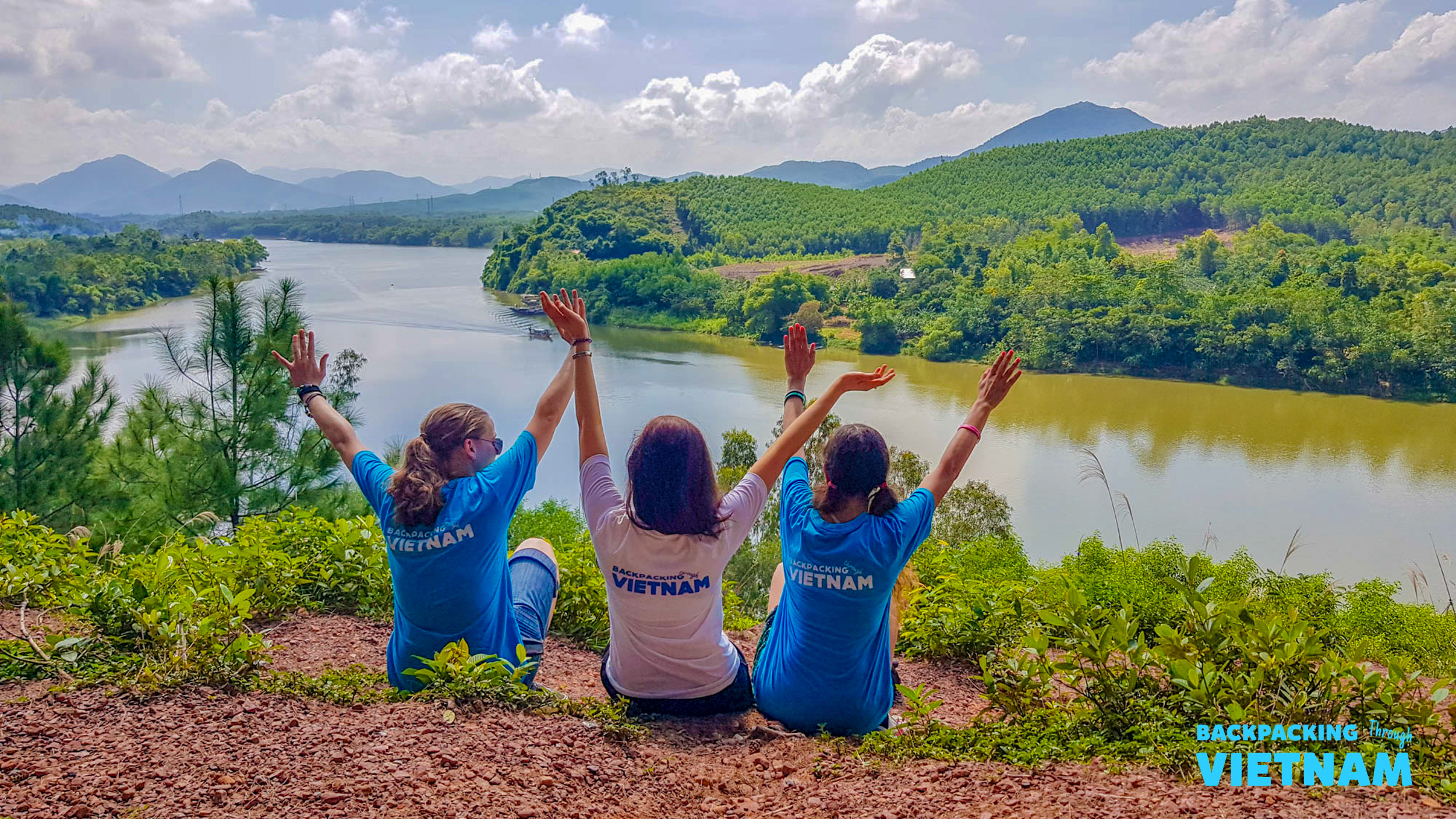 Happy backpackers celebrate a beautiful view of the Perfume River and lush hills near Hue.