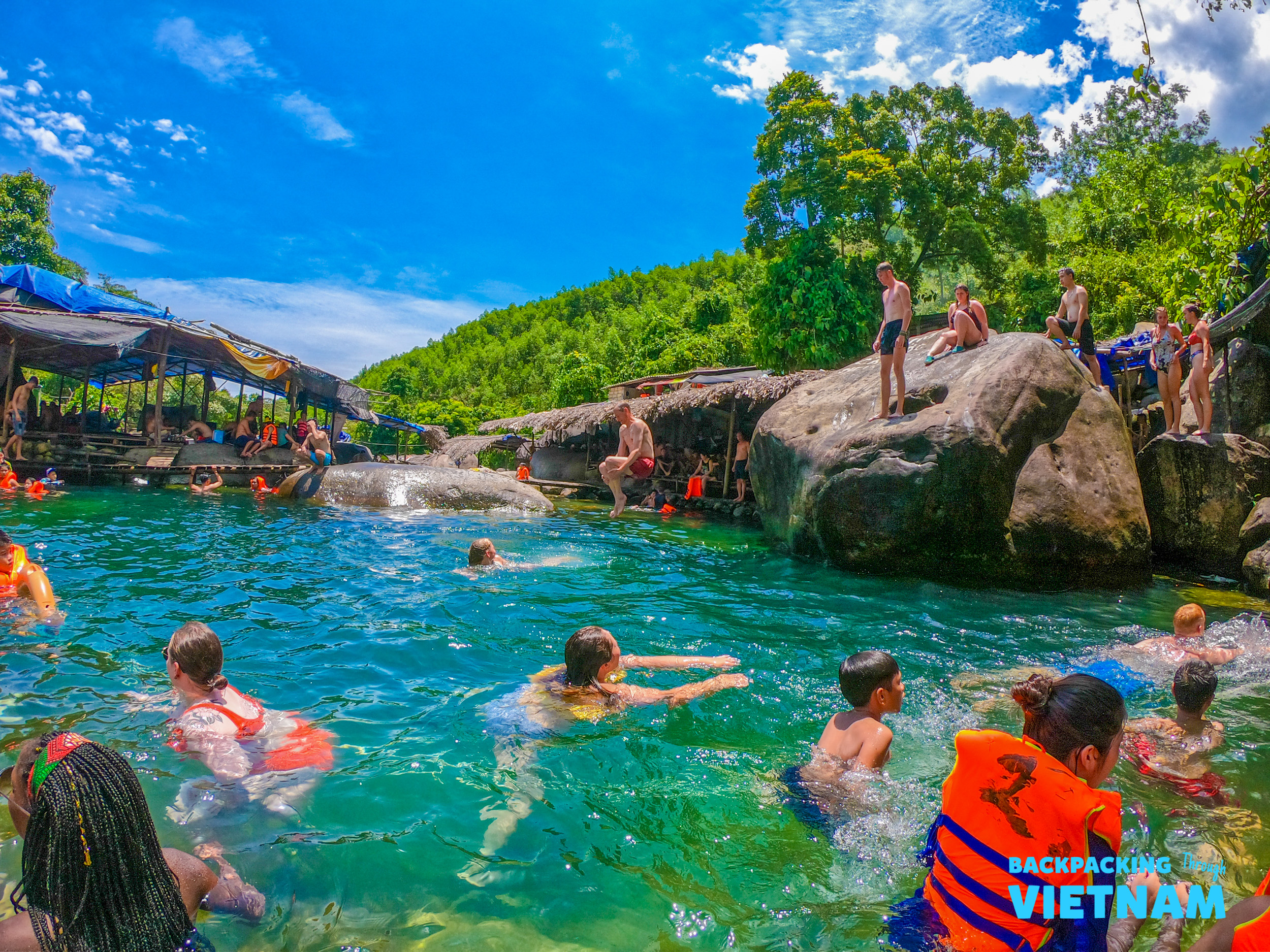Backpackers enjoy a refreshing swim in the clear turquoise waters of a natural spring in Vietnam.