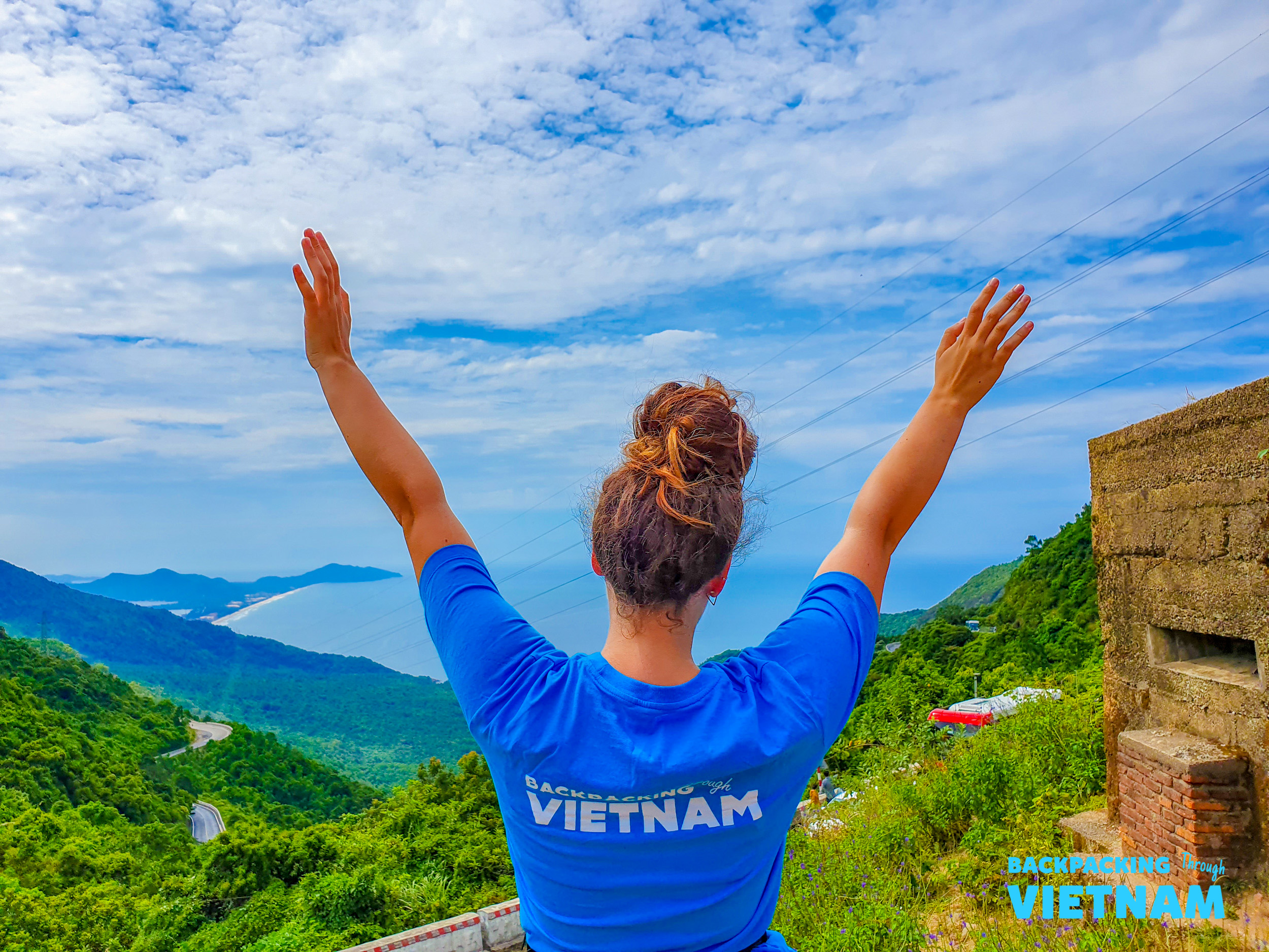 A backpacker on the Hai Van Pass celebrates the stunning coastal views of central Vietnam.