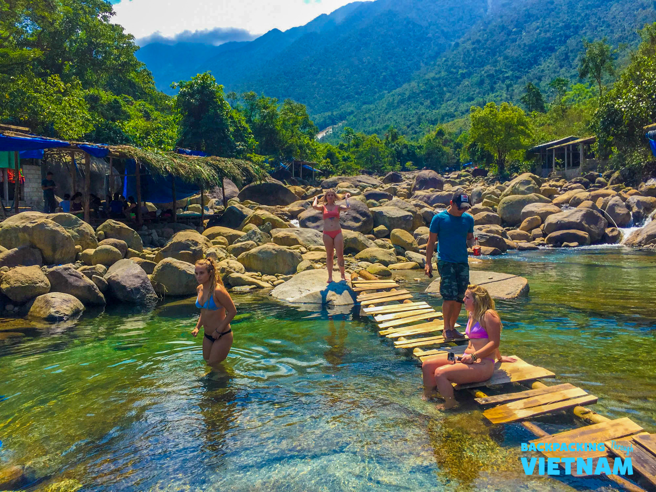 Backpackers cool off in a clear natural spring surrounded by lush mountains in Vietnam.
