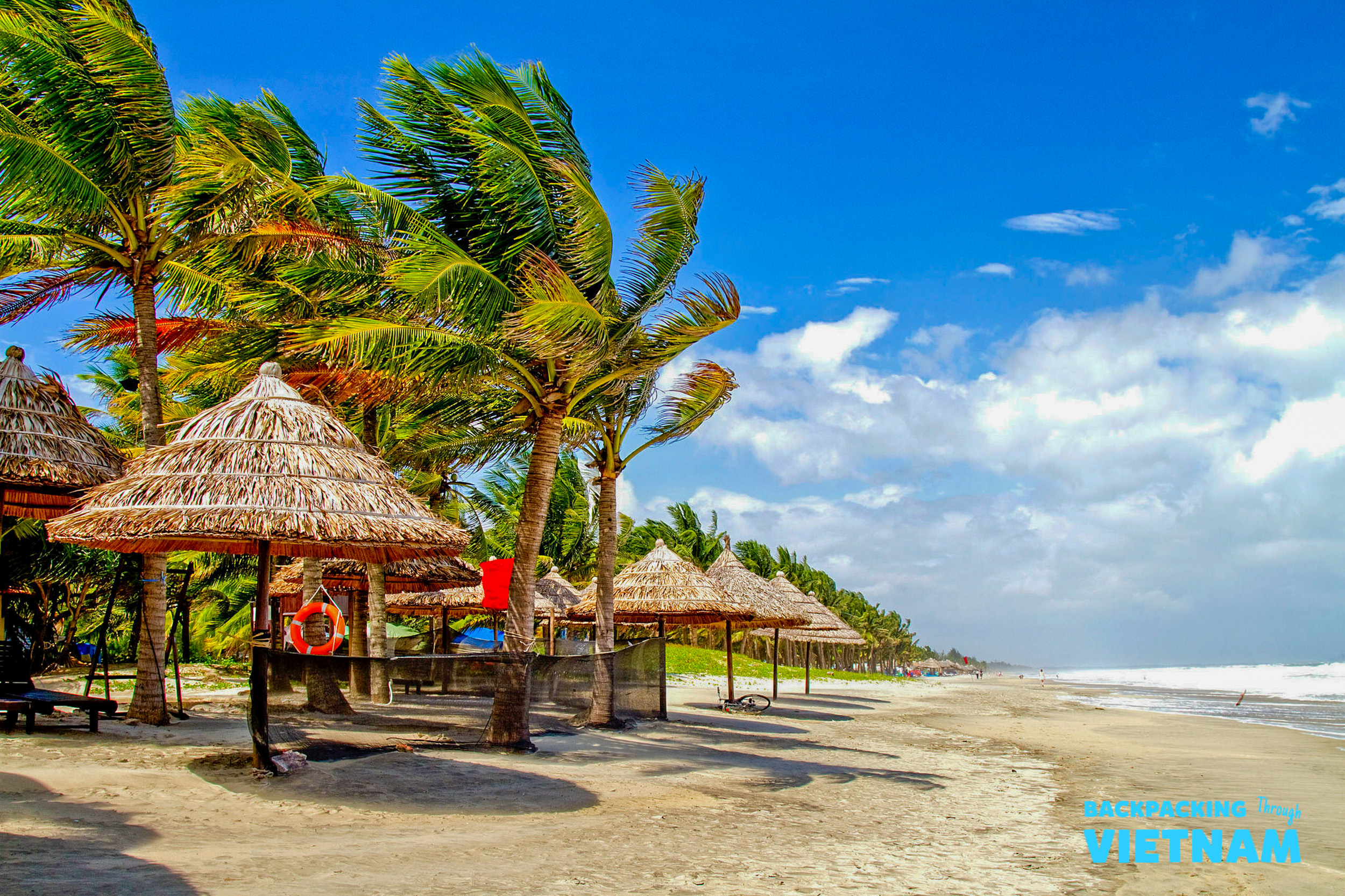 Sunny beach with swaying palm trees and straw umbrellas, perfect for relaxing in Hoi An.