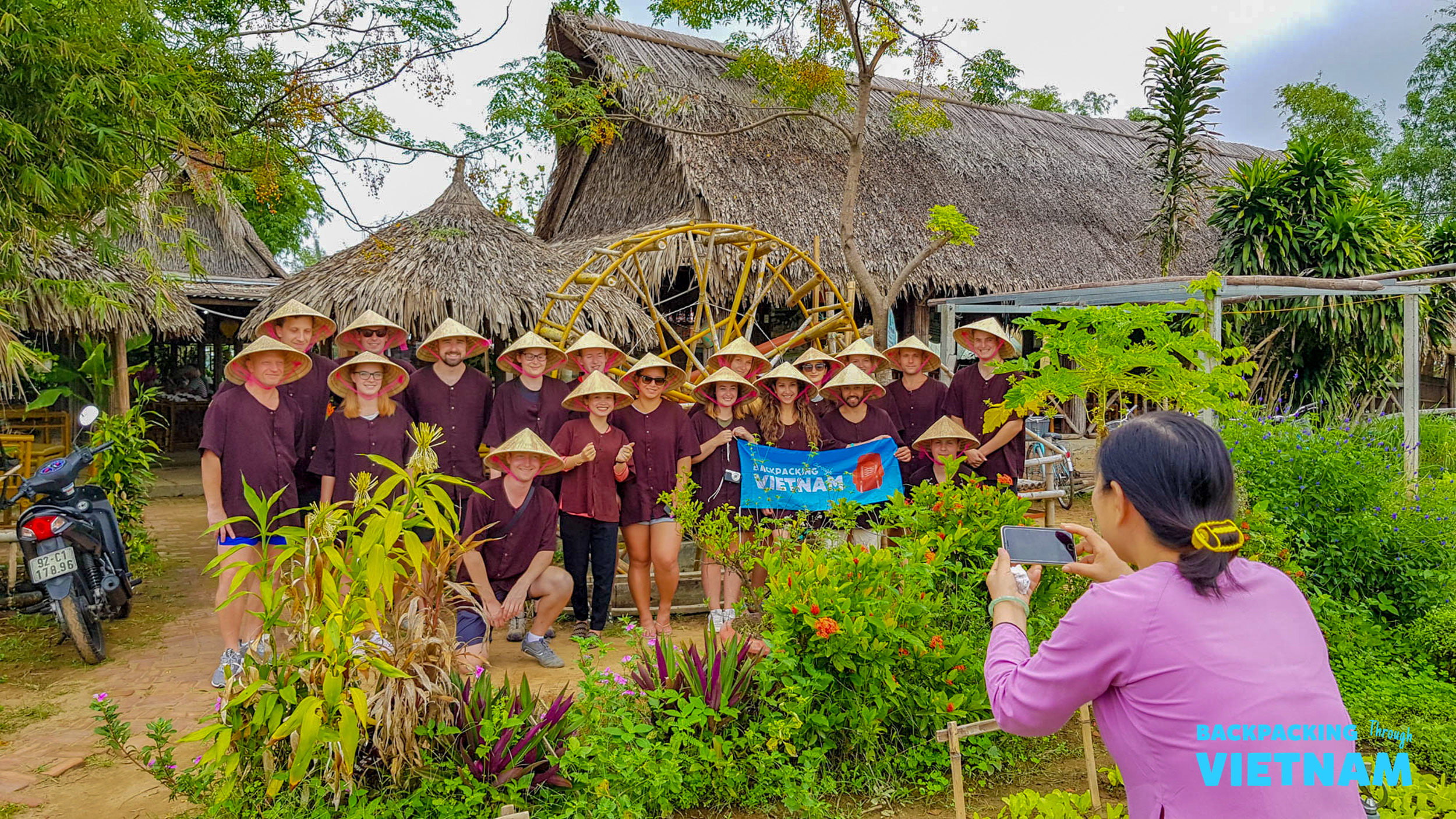 Tourists in traditional conical hats enjoy a cultural experience at a farm in Hoi An, Vietnam.