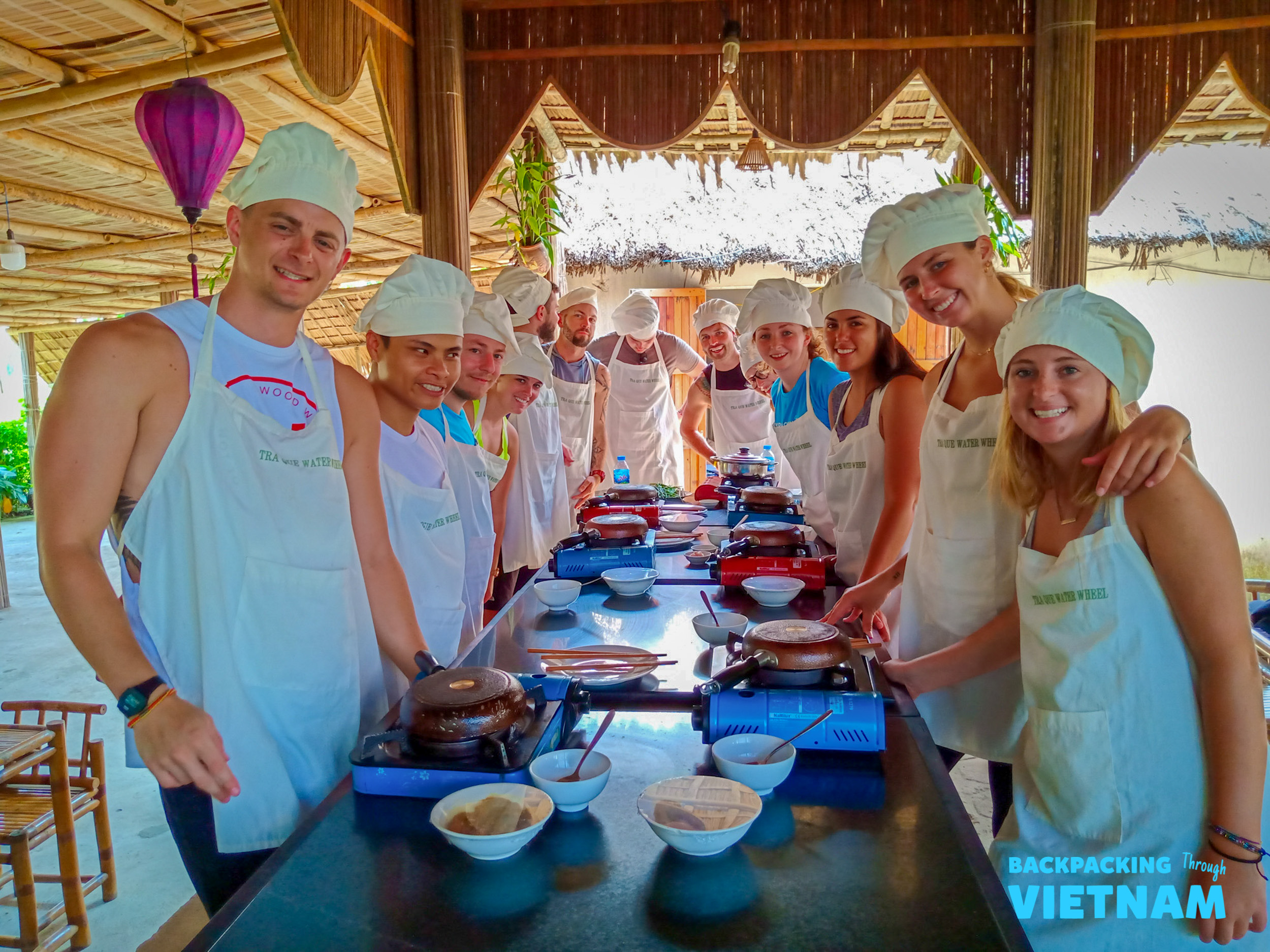 Happy travelers learn to cook traditional Vietnamese dishes at a lively cooking class in Hoi An.
