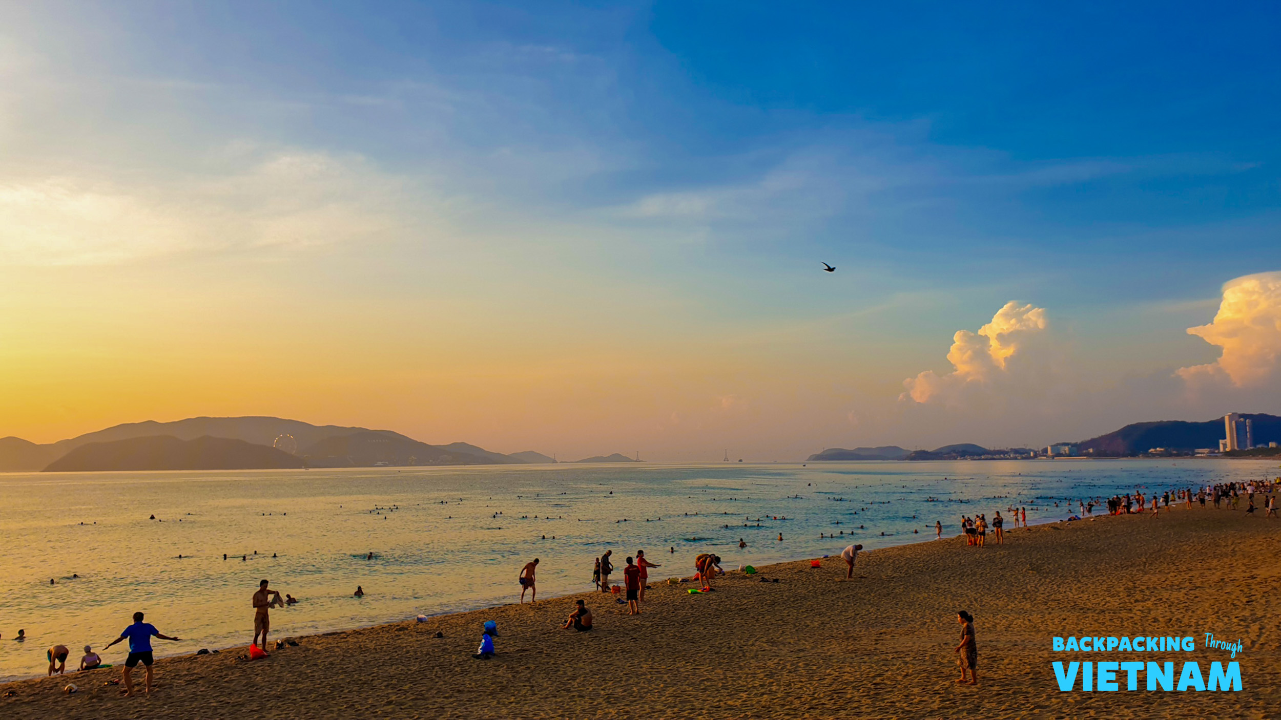 Many people enjoy a beautiful sunset on the wide sandy beach in Nha Trang, Vietnam.