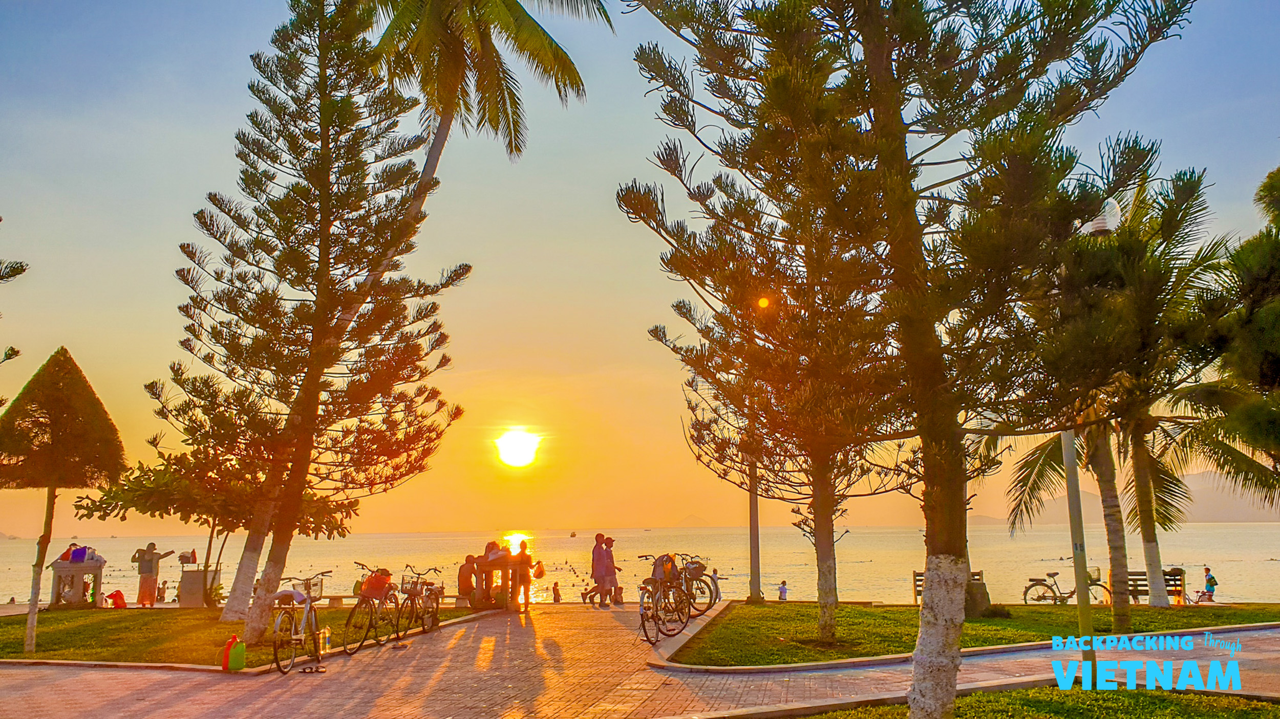 People gather on Nha Trang beach to watch a breathtaking sunset over the calm ocean.