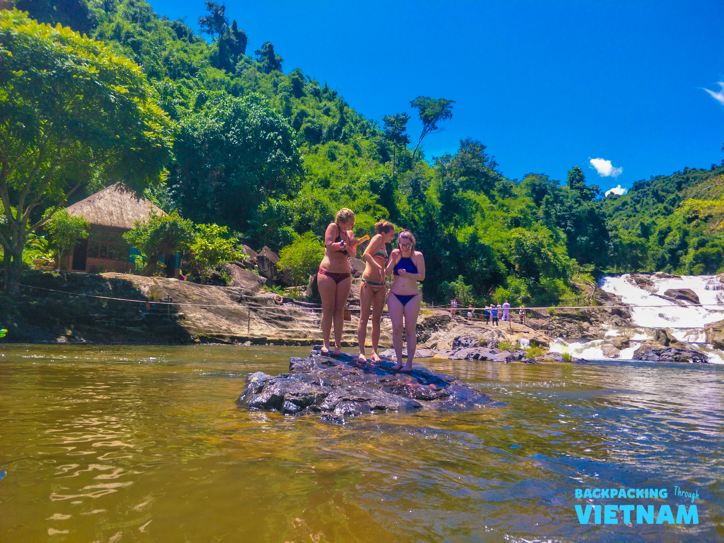 Friends enjoy the refreshing water of a natural river with waterfalls and green mountains in Nha Trang.