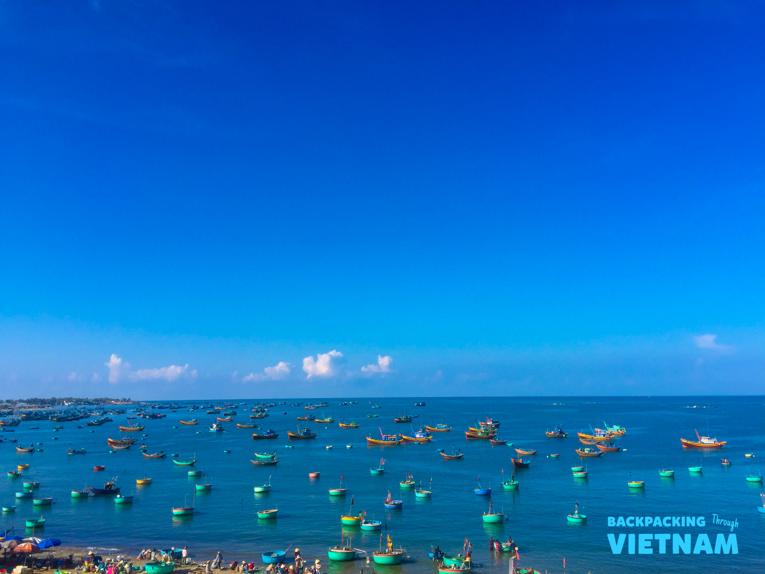 Colorful traditional fishing boats fill the calm blue waters of Mui Ne, Vietnam.