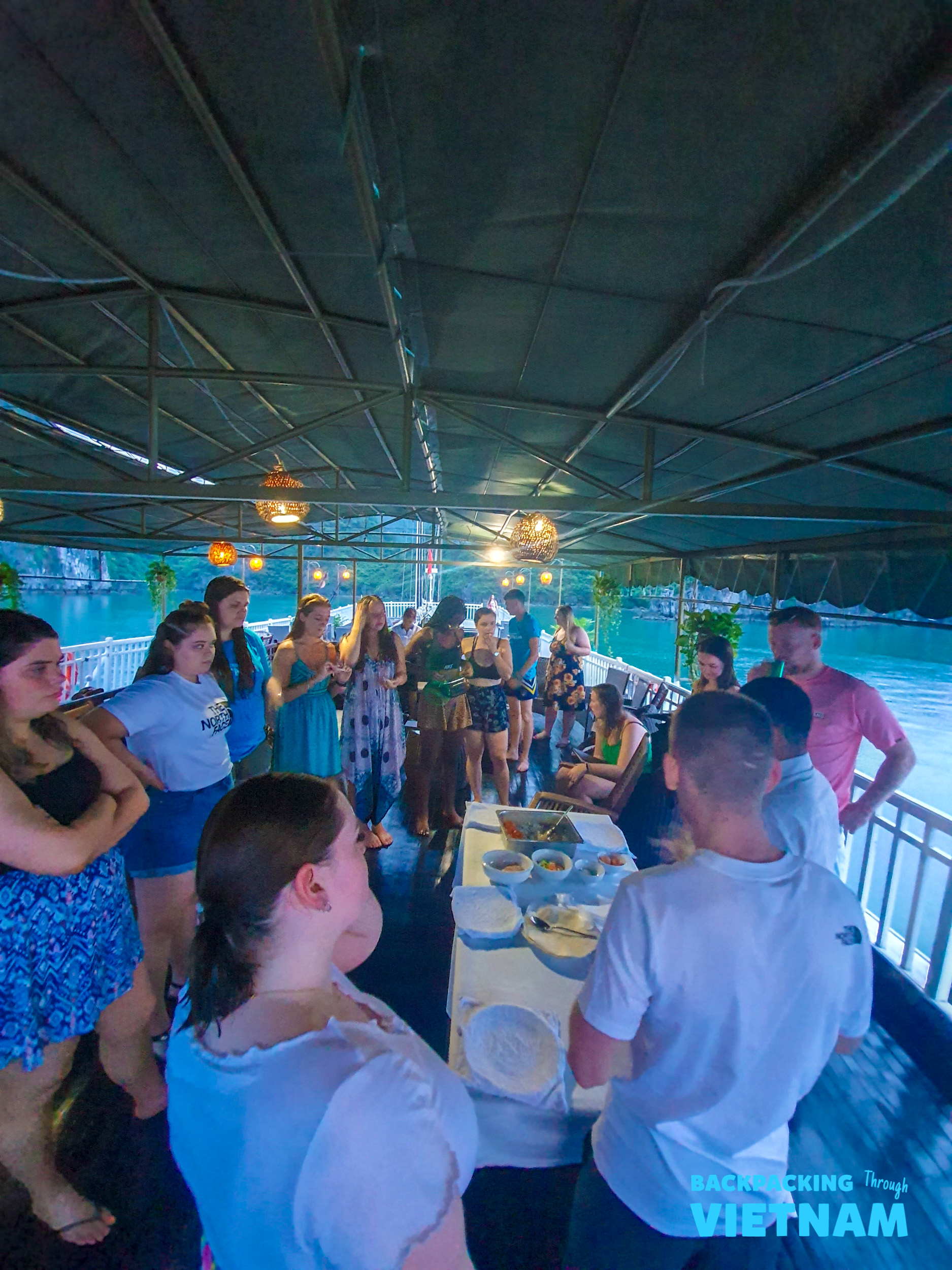 Travelers gather on a boat deck for a cooking lesson in Halong Bay, Vietnam.