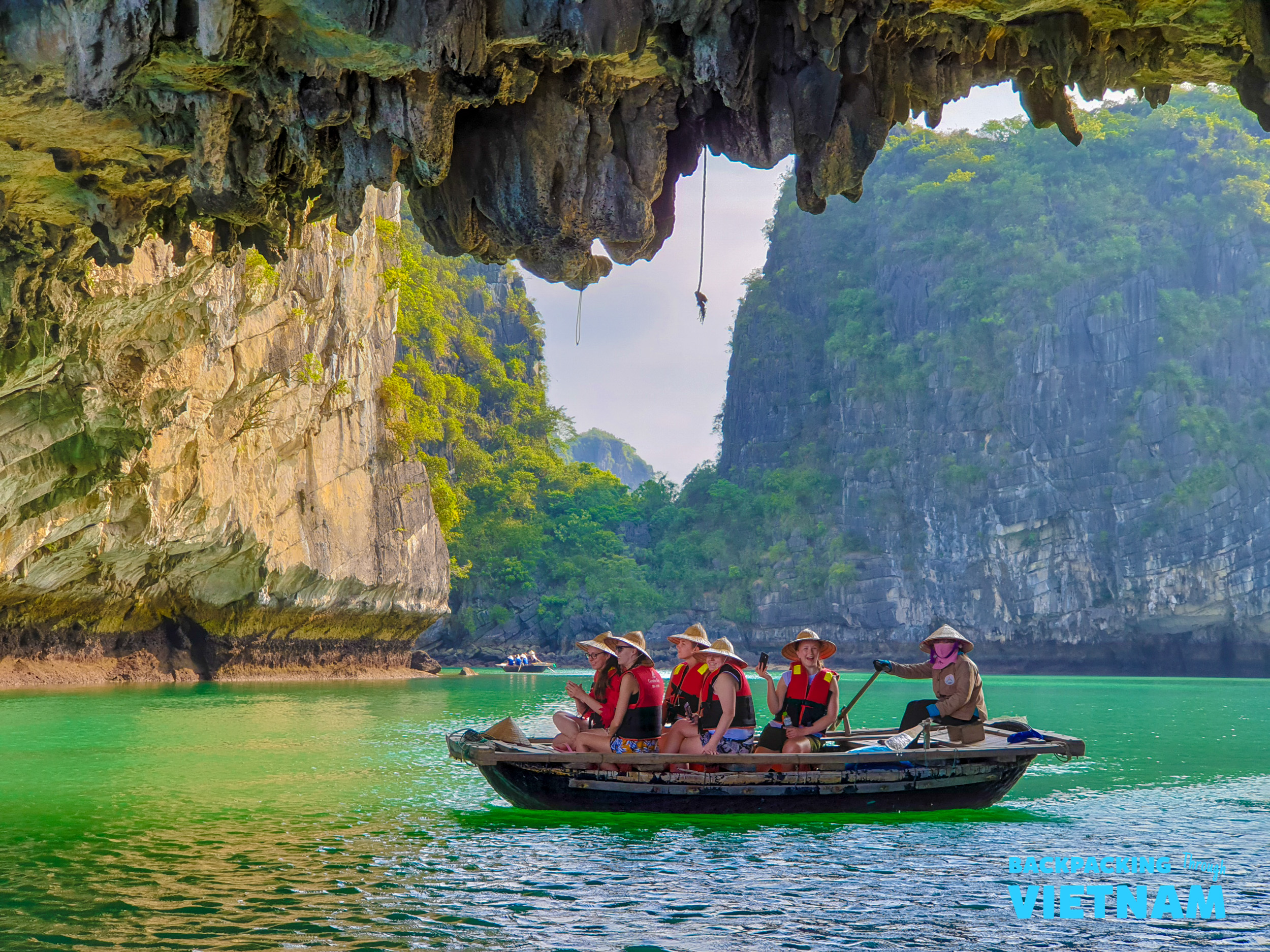 Tourists in hats and life vests enjoy a scenic boat ride through a cave in Tam Coc.