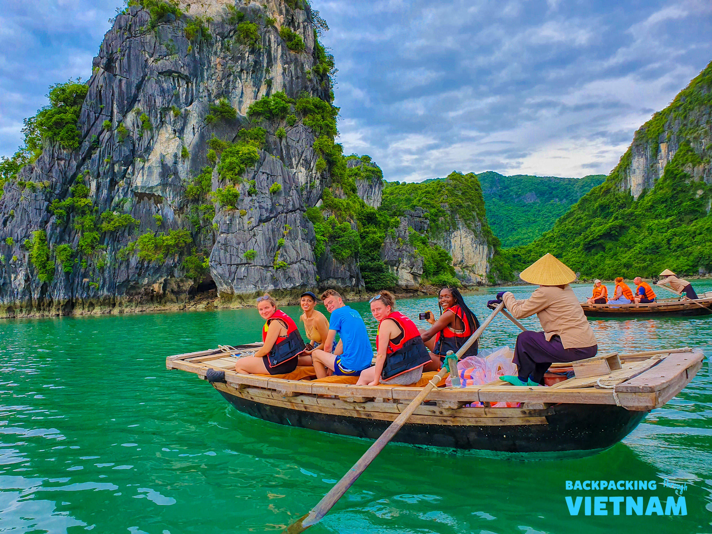 Tourists in life vests enjoy a scenic boat ride through the majestic limestone karsts of Halong Bay.