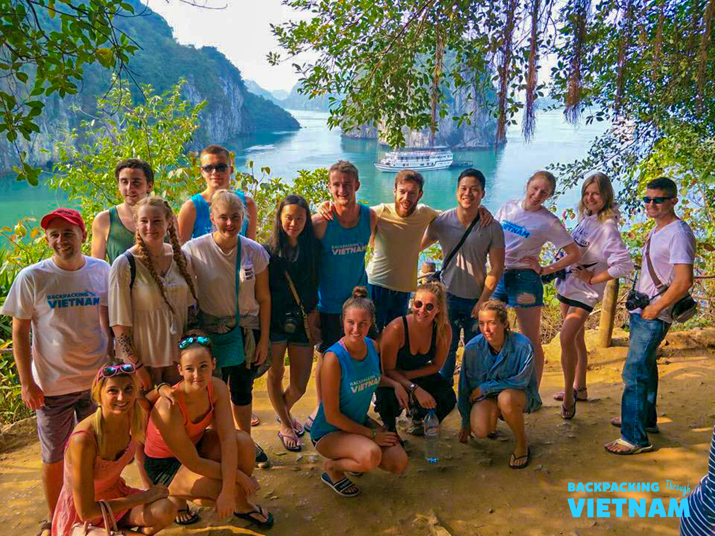 A happy group of backpackers pose for a photo overlooking the stunning Halong Bay.