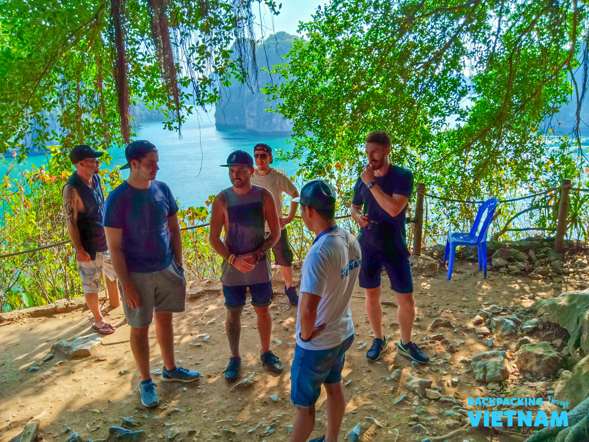 A group of backpackers on a scenic viewpoint, admiring Vietnam's stunning limestone karsts and emerald waters.