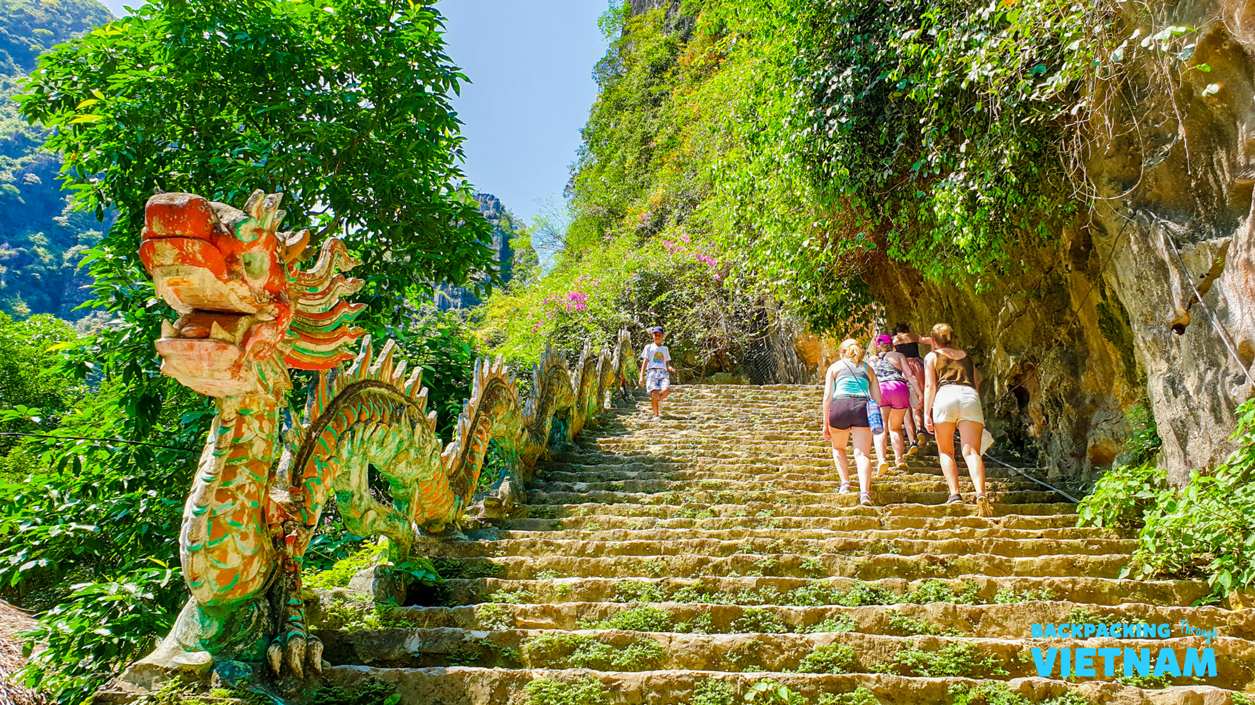A group climbs the ornate dragon-flanked steps of Lying Dragon Mountain in Tam Coc, Vietnam.