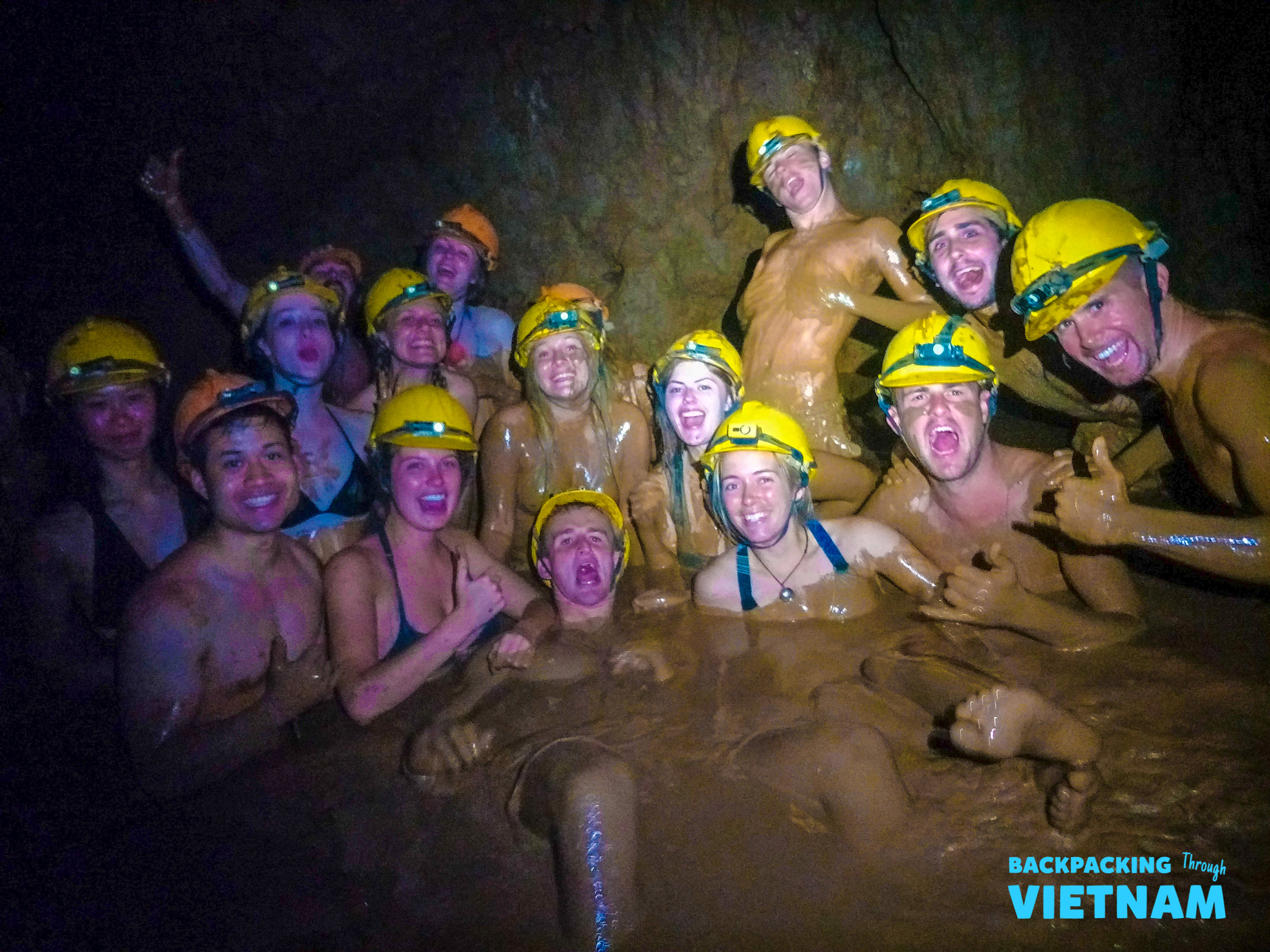 A group of happy backpackers covered in mud and smiling during a fun cave adventure in Phong Nha.