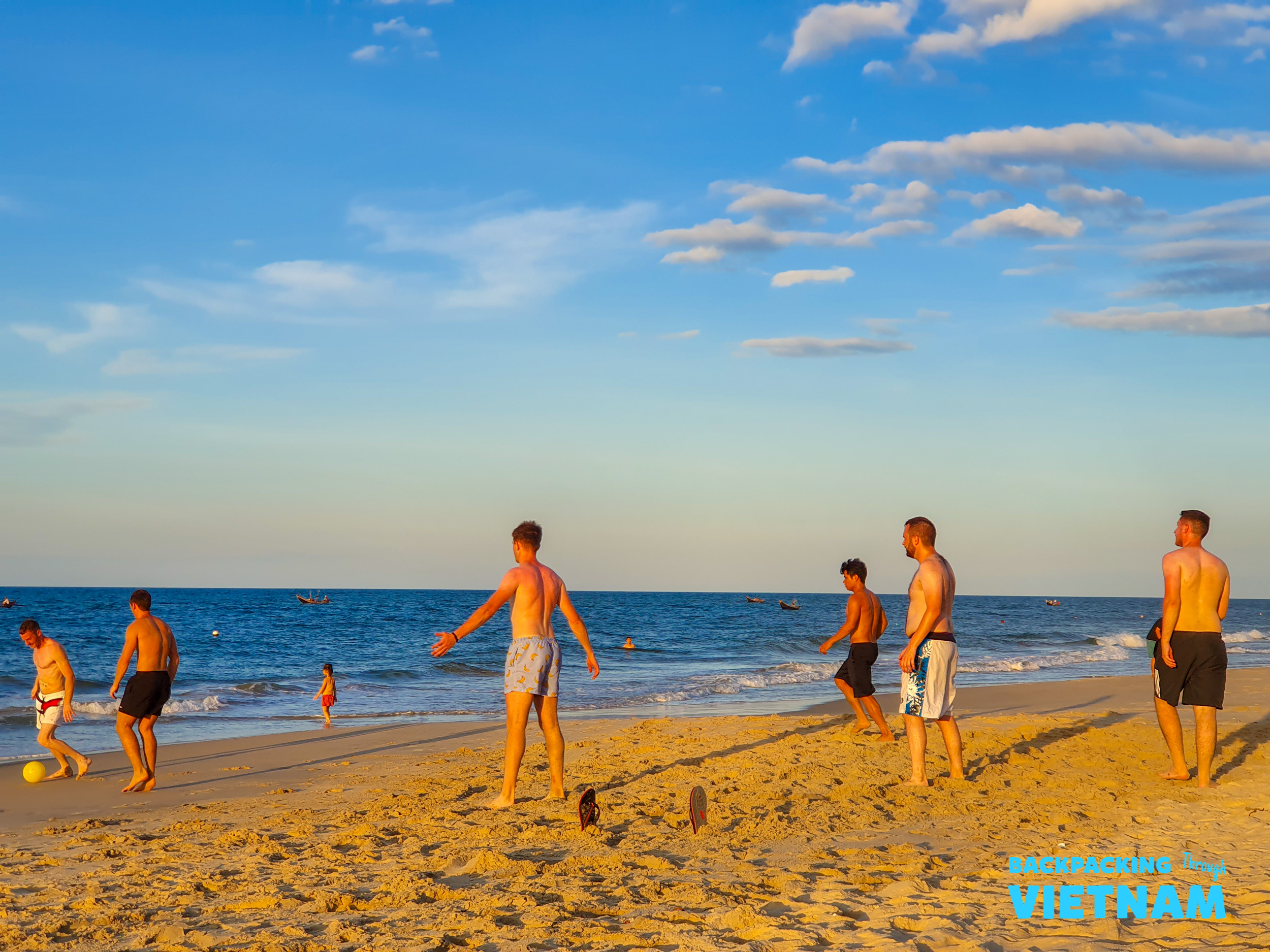 Young men enjoy a lively game of beach soccer on a sunny afternoon in Vietnam.