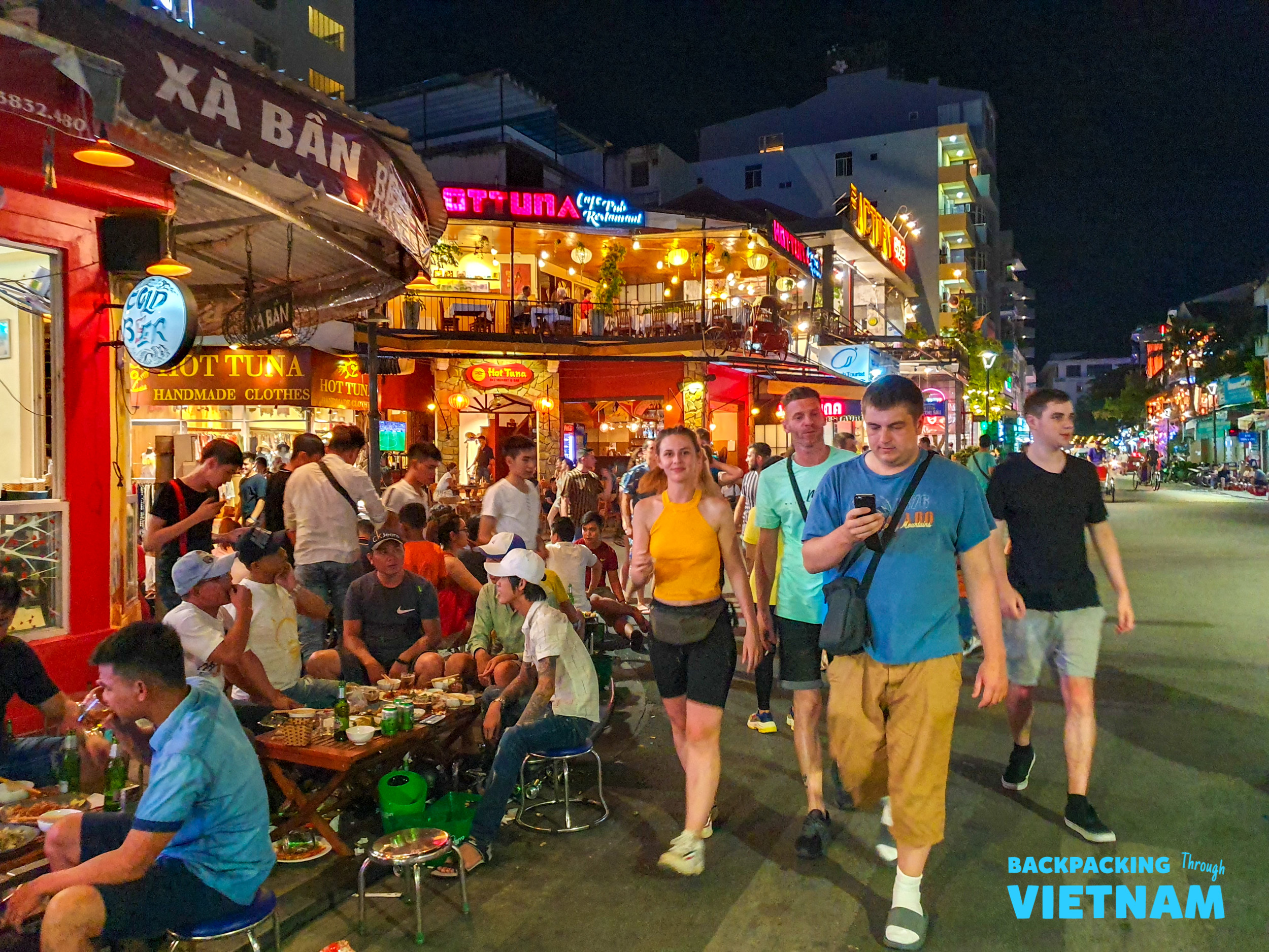 Tourists and locals enjoy a vibrant night out on a bustling street in Hue, Vietnam.