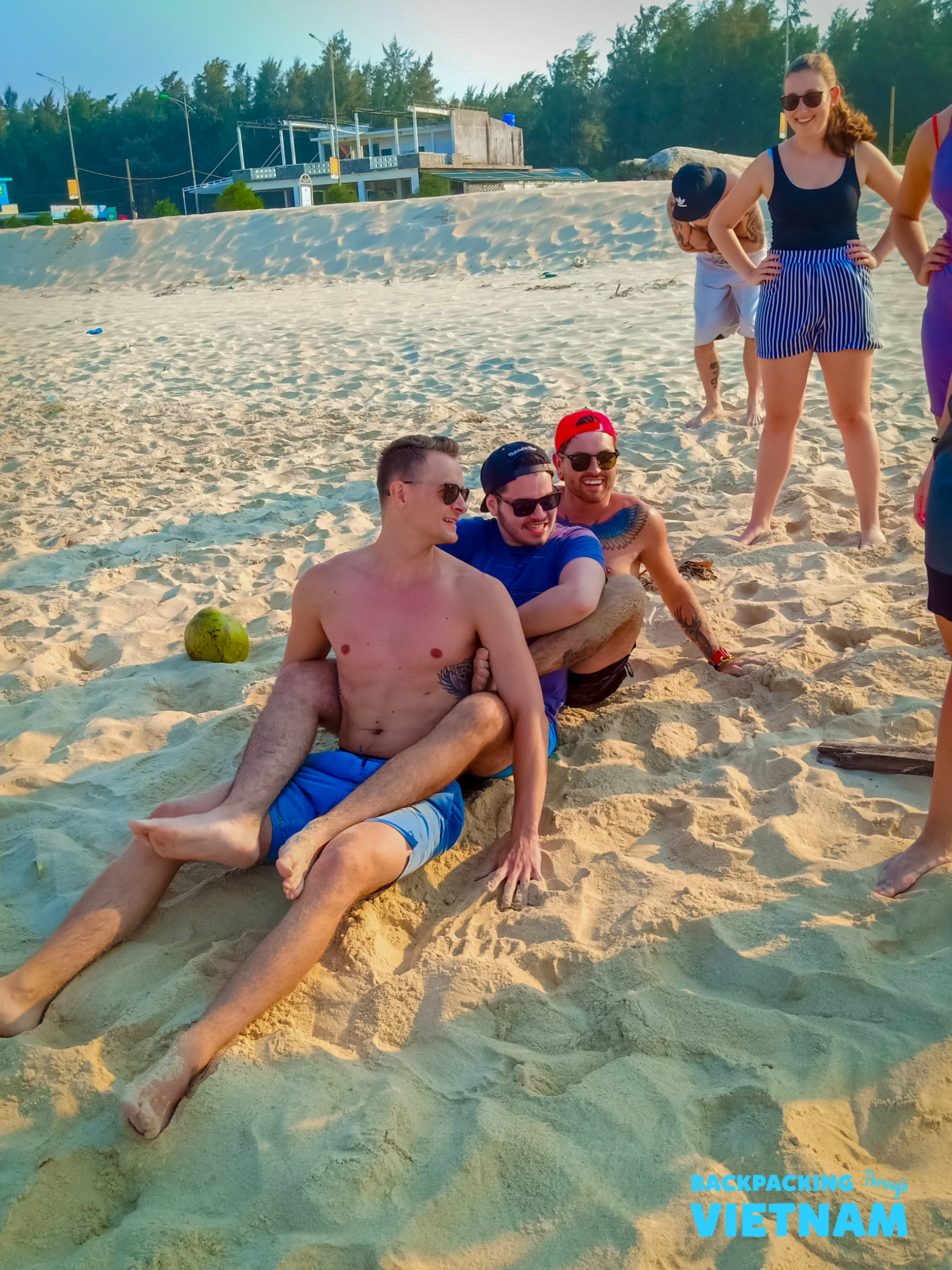 Happy backpackers enjoying a sunny beach day, relaxing and laughing together in Hue, Vietnam.