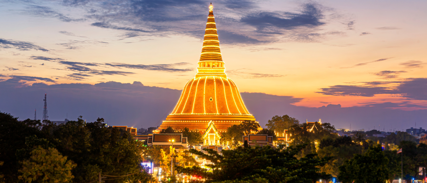The majestic Phra Pathom Chedi glows golden against a vibrant sunset sky in Thailand.