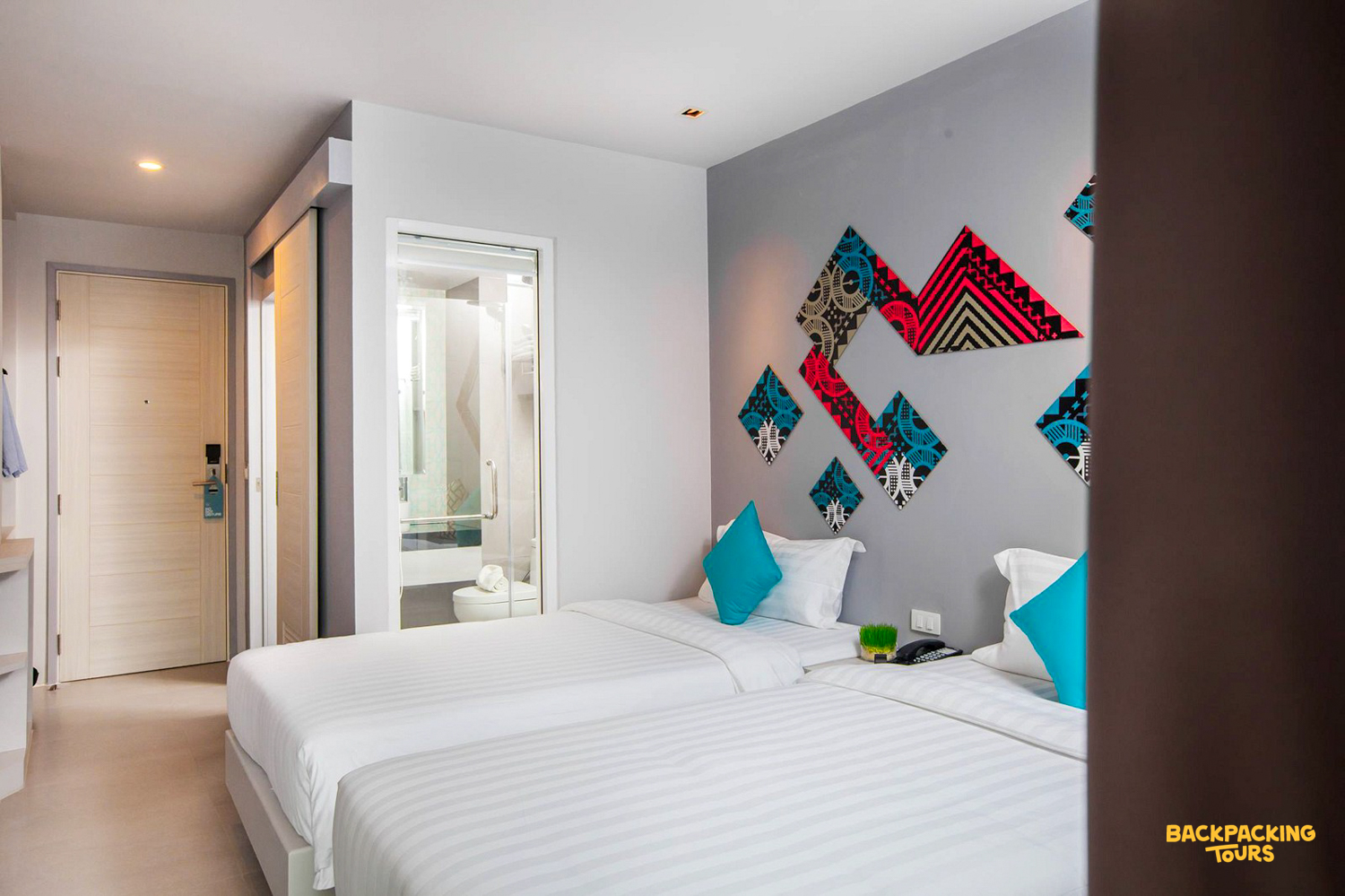 A clean and comfortable twin room in Phuket, featuring vibrant wall decor and a private bathroom.
