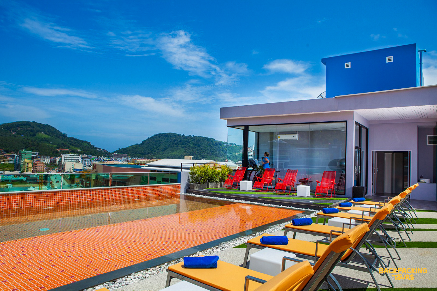 Relaxing rooftop pool deck with sun loungers and city views in sunny Phuket.